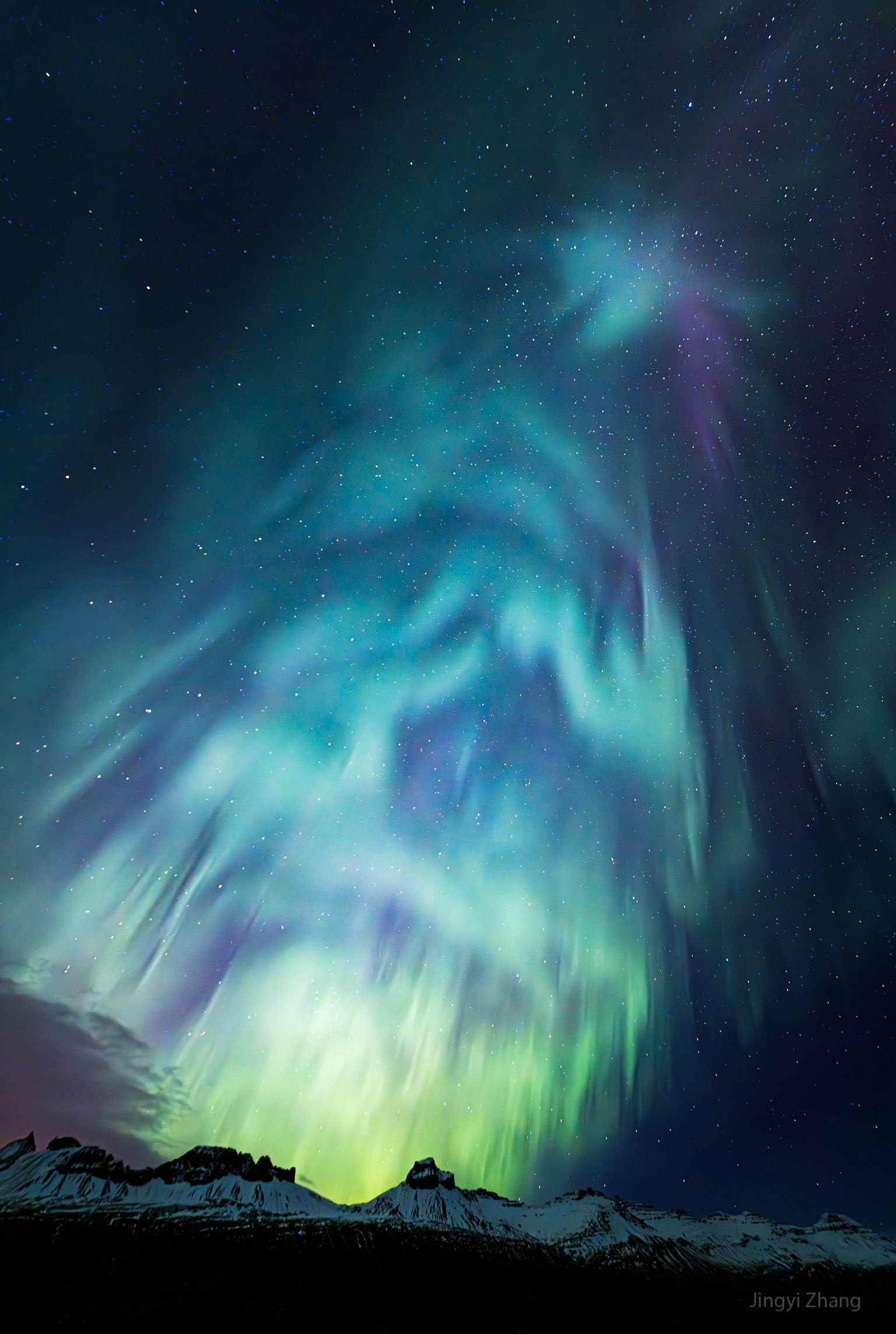 It was December and the sky lit up like a Christmas tree. Shimmering, the vivid green, blue, and purple auroral colors that formed the tree-like apparition were caused by high atmospheric oxygen and nitrogen reacting to a burst of incoming electrons.  Collisions caused the orbital electrons of atoms and molecules to jump into excited energy states and emit visible light when returning to their normal state. The featured image was captured in Djúpivogur, Iceland during the last month of 2023. Our Sun is currently in its most energetic phase of its 11-year cycle, with its high number of active regions and sunspots likely to last into next year. Of course, the Sun has been near solar maximum during this entire year, with its outbursts sometimes resulting in spectacular Earthly auroras.    Image Processors: Take NASA's Astrophoto Challenge