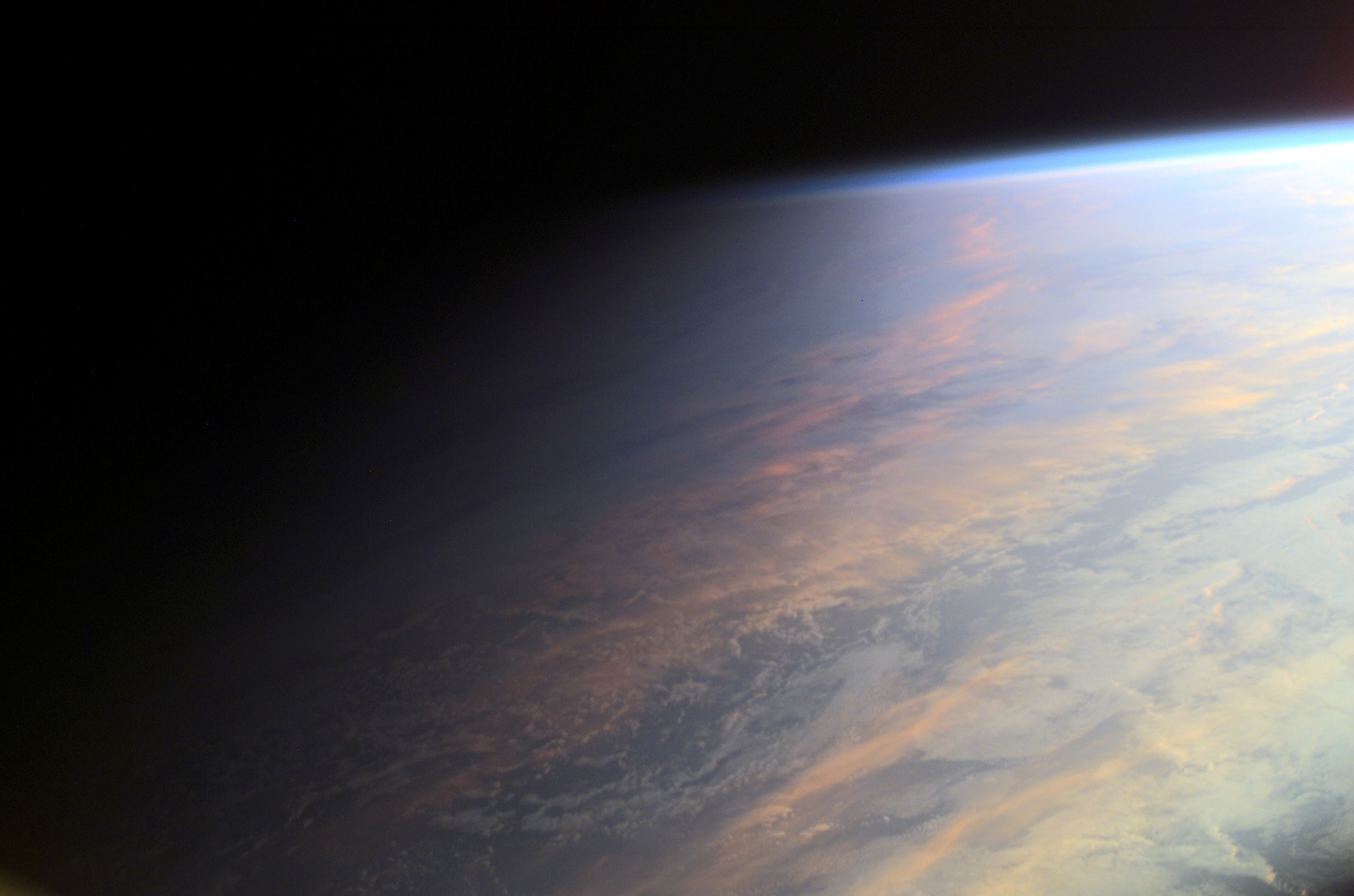 No sudden, sharp boundary marks the passage of day into night in this gorgeous view of ocean and clouds over our fair planet Earth. Instead, the shadow line or terminator is diffuse and shows the gradual transition to darkness we experience as twilight. With the Sun illuminating the scene from the right, the cloud tops reflect gently reddened sunlight filtered through the dusty troposphere, the lowest layer of the planet's nurturing atmosphere. A clear high altitude layer, visible along the dayside's upper edge, scatters blue sunlight and fades into the blackness of space. This picture was taken from the International Space Station orbiting at an altitude of 211 nautical miles. Of course from home, you can check out the Earth Now.