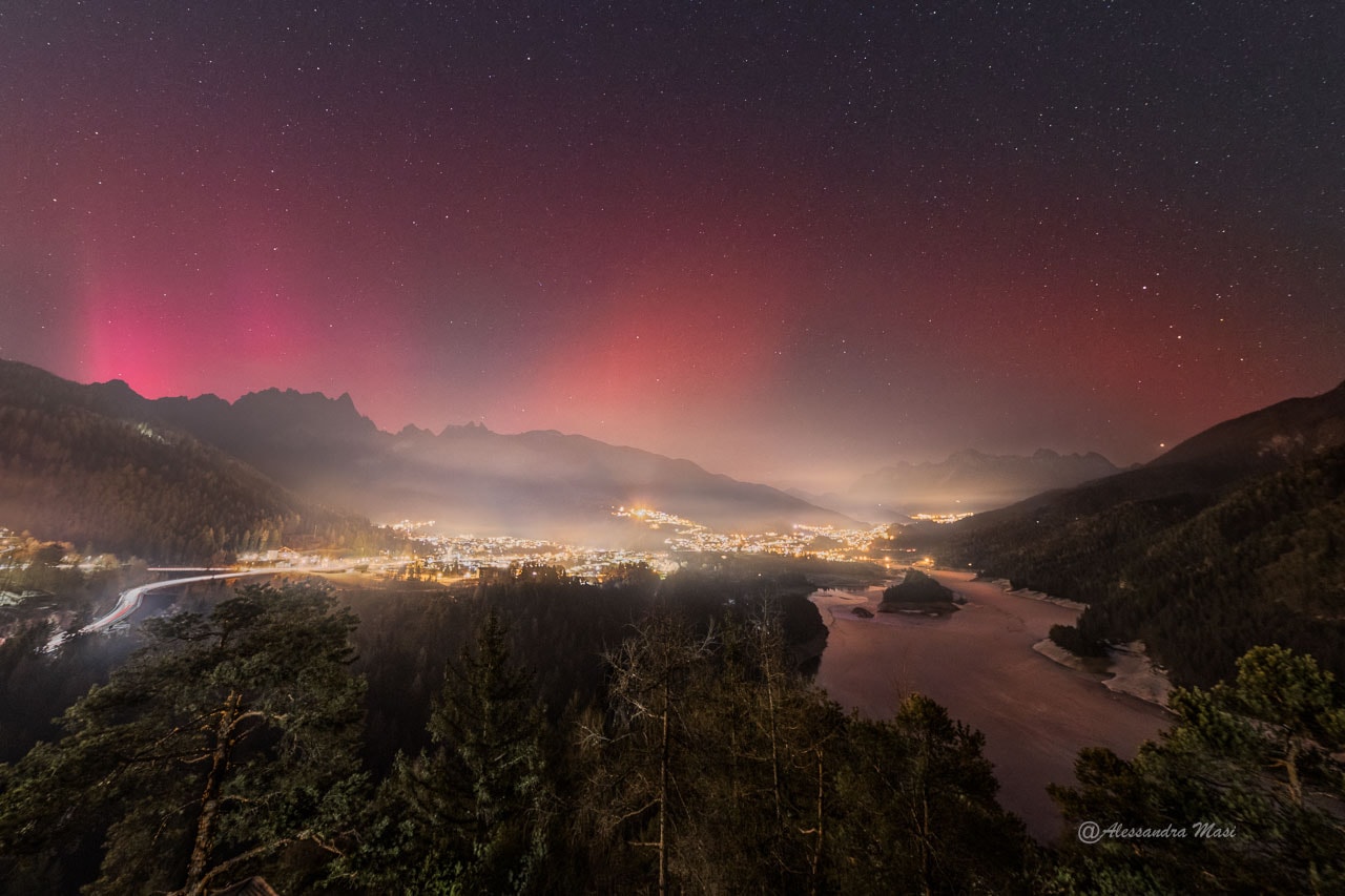 It was a new year, and the sky was doubly red.  The new year meant that the Earth had returned to its usual place in its orbit on January 1, a place a few days before its closest approach to the Sun.  The first of the two red skyglows, on the left, was a red aurora, complete with vertical rays, caused by a blast from the Sun pushing charged particles into Earth's atmosphere.  The second red glow, most prominent on the far right, was possibly a SAR arc caused by a river of charged particles flowing across Earth's atmosphere.  Although both appear red, the slight color difference is likely due to the aurora being emitted by both oxygen and nitrogen, whereas the higher SAR arc was possibly emitted more purely by atmospheric oxygen. The featured image was taken on January 1 from near Pieve di Cadore in Italy.   Portal Universe: Random APOD Generator