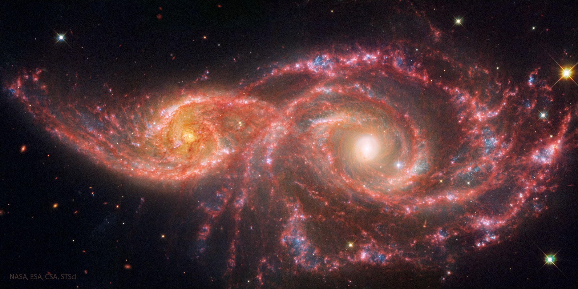 Billions of years from now, only one of these two galaxies will remain.  Until then, spiral galaxies NGC 2207 and IC 2163 will slowly pull each other apart, creating tides of matter, sheets of shocked gas, lanes of dark dust, bursts of star formation, and streams of cast-away stars.  The featured image in scientifically assigned colors is a composite of Hubble exposures in visible light and Webb exposures in infrared light. Astronomers predict that NGC 2207, the larger galaxy on the right, will eventually incorporate IC 2163, the smaller galaxy on the left.  In the most recent encounter that about peaked 40 million years ago, the smaller galaxy is swinging around counter-clockwise and is now slightly behind the larger galaxy.  The space between stars is so vast that when galaxies collide, the stars in them usually do not collide.   Jigsaw Challenge: Astronomy Puzzle of the Day