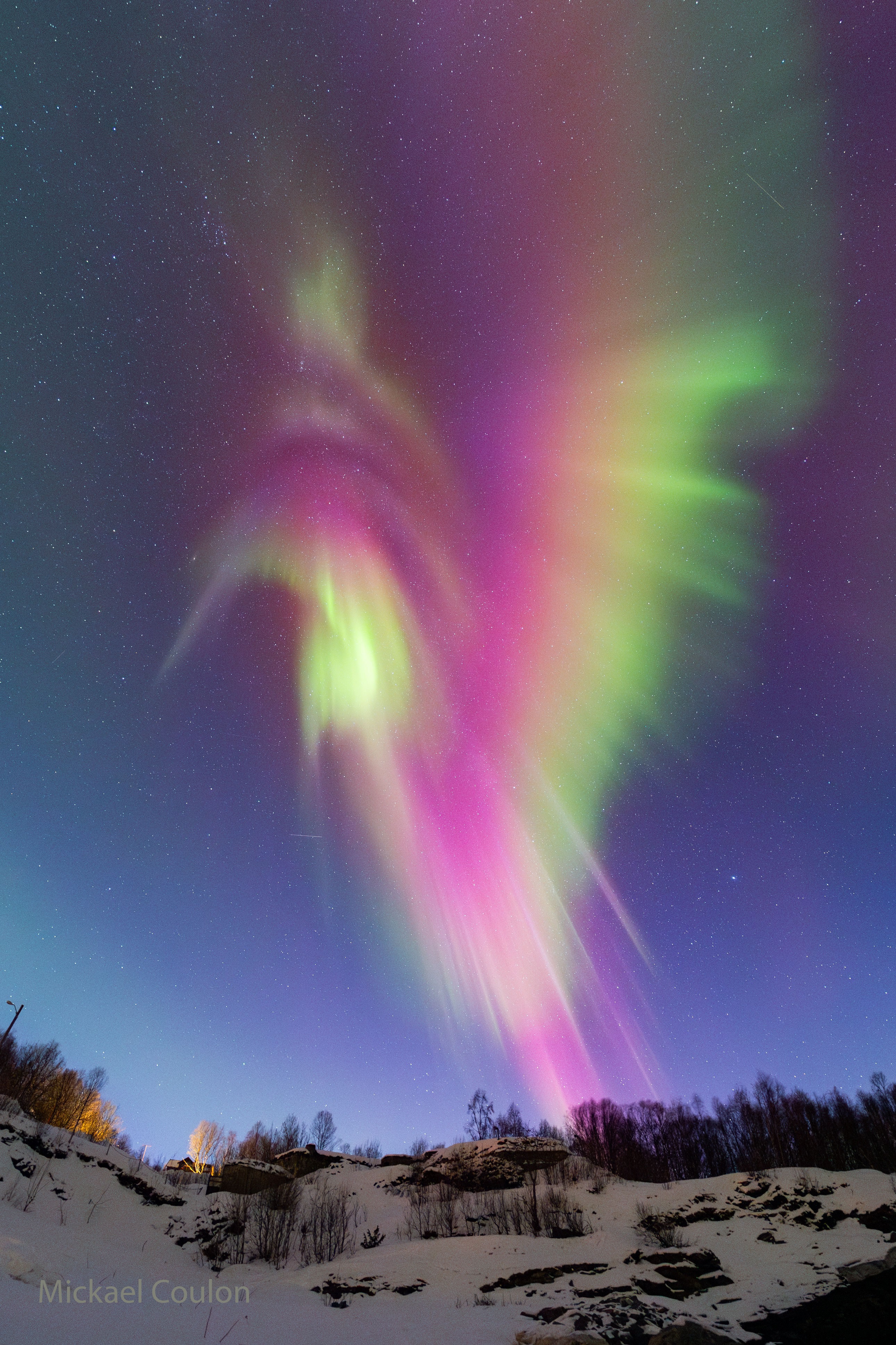 Is this the largest hummingbird ever?  Although it may look like a popular fluttering nectarivore, what is pictured is actually a beautifully detailed and colorful aurora, complete with rays reminiscent of feathers. This aurora was so bright that it was visible to the unaided eye during blue hour -- just after sunset when the sky appears a darkening blue.  However, the aurora only looked like a hummingbird through a sensitive camera able to pick up faint glows. As reds typically occurring higher in the Earth's atmosphere than the greens, the real 3D shape of this aurora would likely appear unfamiliar.  Auroras are created when an explosion on the Sun causes high energy particles to flow into the Earth's atmosphere and excite atoms and molecules of nitrogen and oxygen.  The featured image was captured about two weeks ago above Lyngseidt, Norway.