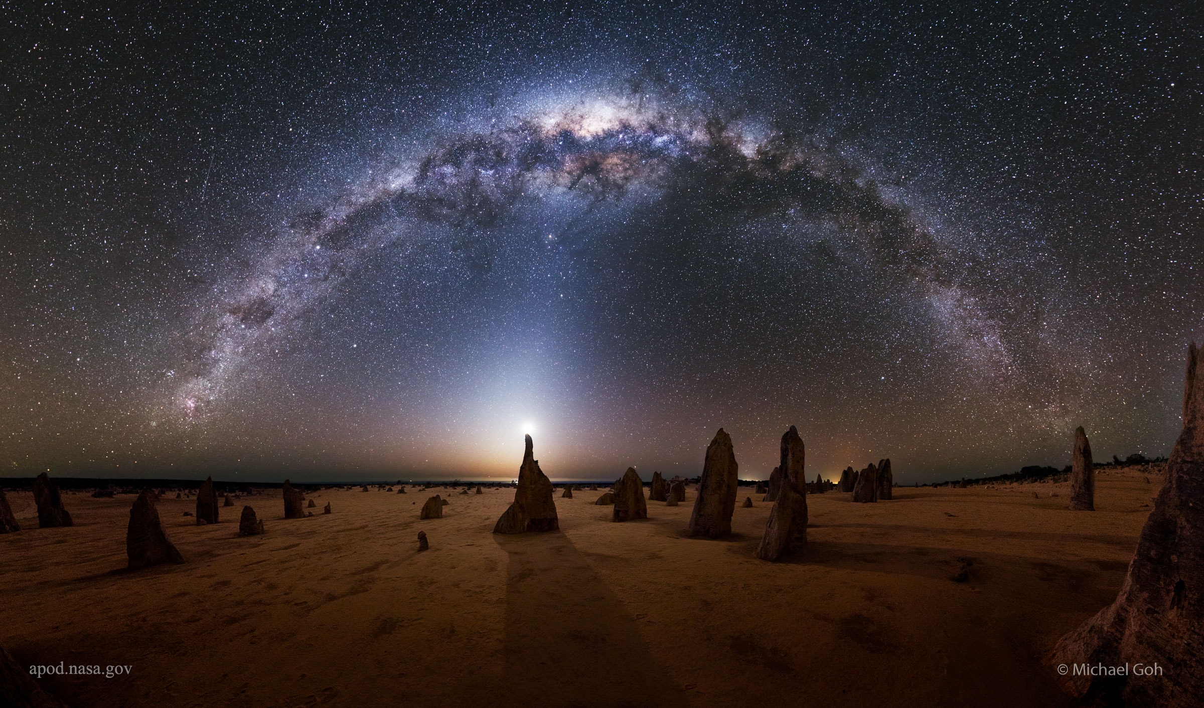 What strange world is this? Earth. In the foreground of the featured image are the Pinnacles, unusual rock spires in Nambung National Park in Western Australia. Made of ancient sea shells (limestone), how these human-sized picturesque spires formed remains unknown.  In the background, just past the end of the central Pinnacle, is a bright crescent Moon. The eerie glow around the Moon is mostly zodiacal light, sunlight reflected by dust grains orbiting between the planets in the Solar System. Arching across the top is the central band of our Milky Way Galaxy. Many famous stars and nebulas are also visible in the background night sky. The featured 29-panel panorama was taken and composed in 2015 September after detailed planning that involved the Moon, the rock spires, and their corresponding shadows. Even so, the strong zodiacal light was a pleasant surprise.   Your Sky Surprise: What picture did APOD feature on your birthday? (post 1995)