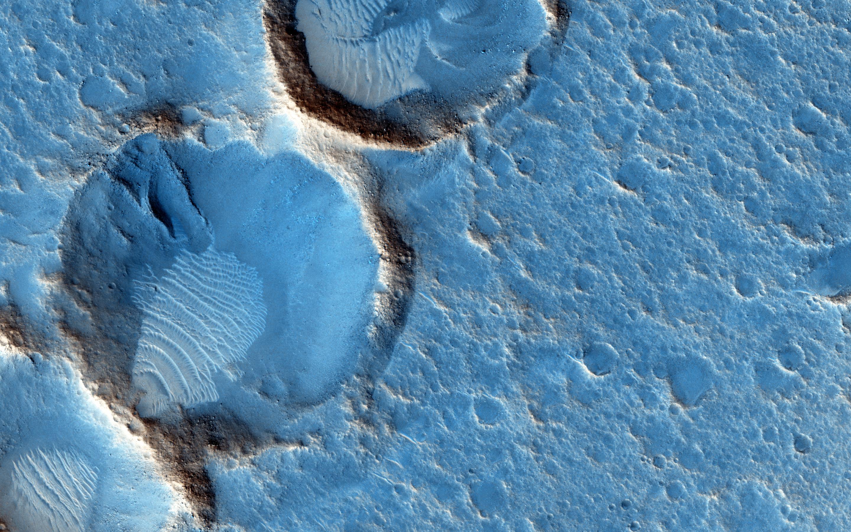This close-up from the Mars Reconnaissance Orbiter's HiRISE camera shows weathered craters and windblown deposits in southern Acidalia Planitia. A striking shade of blue in standard HiRISE image colors, to the human eye the area would probably look grey or a little reddish. But human eyes have not gazed across this terrain, unless you count the eyes of NASA astronauts in the sci-fi novel, "The Martian," by Andy Weir. The novel chronicles the adventures of Mark Watney, an astronaut stranded at the fictional Mars mission Ares 3 landing site, corresponding to the coordinates of this cropped HiRISE frame. For scale, Watney's 6-meter-diameter habitat at the site would be about 1/10th the diameter of the large crater. Of course, the Ares 3 landing coordinates are only about 800 kilometers north of the (real life) Carl Sagan Memorial Station, the 1997 Pathfinder landing site.