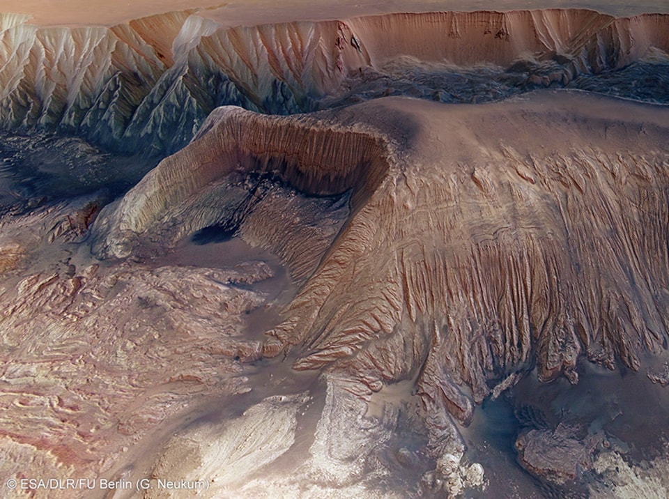 What's happened in Hebes Chasma on Mars? Hebes Chasma is a depression just north of the enormous Valles Marineris canyon.  Since the depression is unconnected to other surface features, it is unclear where the internal material went. Inside Hebes Chasma is Hebes Mensa, a 5 kilometer high mesa that appears to have undergone an unusual partial collapse -- a collapse that might be providing clues. The featured image, taken by ESA's robotic Mars Express spacecraft currently orbiting Mars, shows great details of the chasm and the unusual horseshoe shaped indentation in the central mesa. Material from the mesa appears to have flowed onto the floor of the chasm, while a possible dark layer appears to have pooled like ink on a downslope landing.  One hypothesis holds that salty rock composes some lower layers in Hebes Chasma, with the salt dissolving in melted ice flows that drained through holes into an underground aquifer.