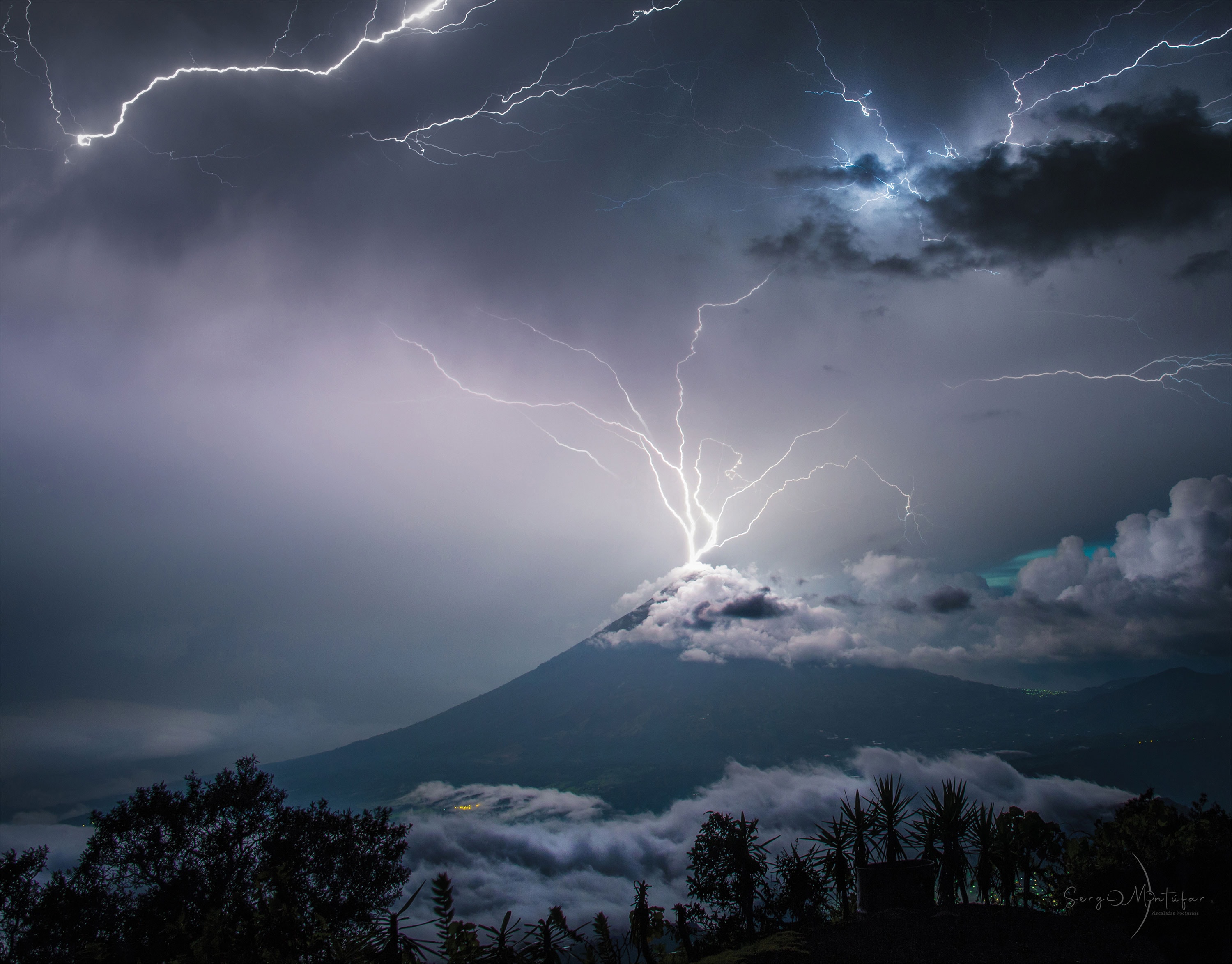 Have you ever watched a lightning storm in awe?  You're not alone. Details of what causes lightning are still being researched, but it is known that inside some clouds, internal updrafts cause collisions between ice and snow that slowly separate charges between cloud tops and bottoms. The rapid electrical discharges that are lightning soon result.  Lightning usually takes a jagged course, rapidly heating a thin column of air to about three times the surface temperature of the Sun.  The resulting shock wave starts supersonically and decays into the loud sound known as thunder.  On average, around the world, about 6,000 lightning bolts occur between clouds and the Earth every minute. Pictured in July 2019 in a two-image composite, lightning stems from communication antennas near the top of Volcán de Agua (Volcano of Water) in Guatemala.  Sky Surprise: What picture did APOD feature on your birthday? (post 1995)