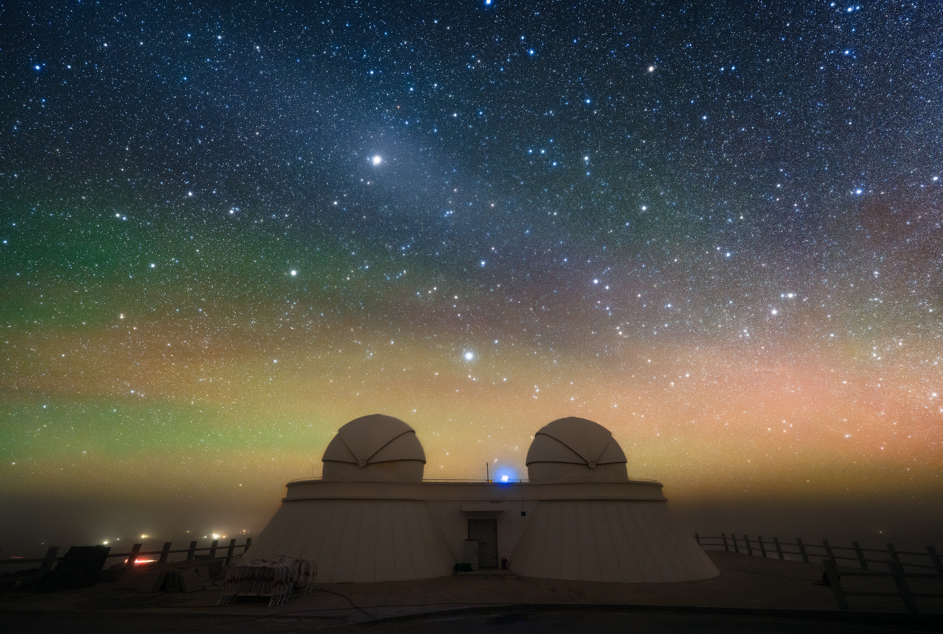 This year Saturn was at opposition on September 21, opposite the Sun in planet Earth's sky. At its closest to Earth, Saturn was also at its brightest of the year, rising as the Sun set and shining above the horizon all night long among the fainter stars of the constellation Pisces. In this snapshot from the Qinghai Lenghu Observatory, Tibetan Plateau, southwestern China, the outer planet is immersed in a faint, diffuse oval of light known as the gegenschein or counter glow. The diffuse gegenschein is produced by sunlight backscattered by interplanetary dust along the Solar System's ecliptic plane, opposite the Sun in planet Earth's sky. Like a giant eye, on this dark night Saturn and gegenschein seem to stare down on the observatory's telescope domes seen against a colorful background of airglow along the horizon.