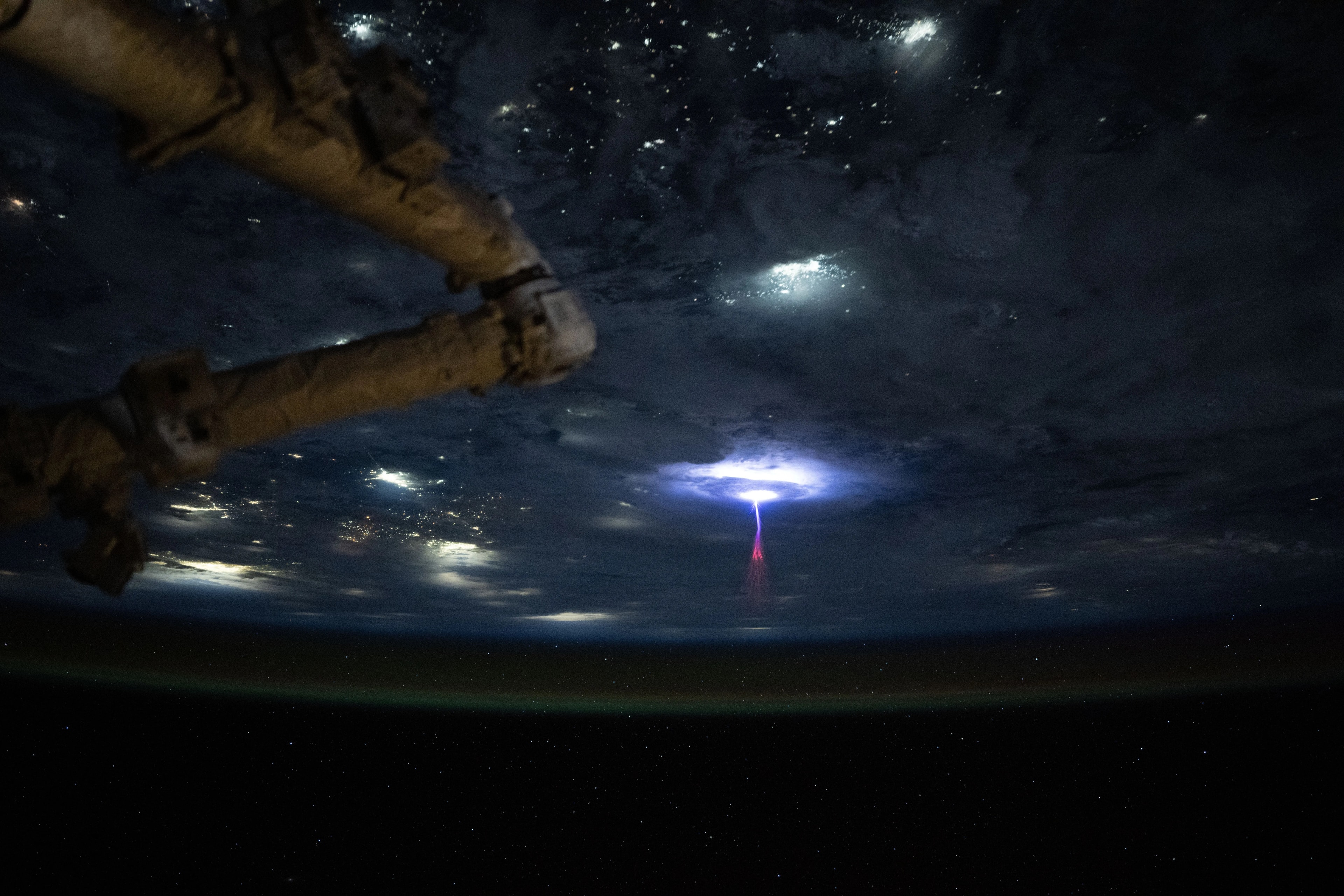 What's that rising up from the Earth? When circling the Earth on the International Space Station early in July, astronaut Nicole Ayers saw an unusual type of lightning rising up from the Earth: a gigantic jet. The powerful jet appears near the center of the featured image in red, white, and blue. Giant jet lightning has only been known about for the past 25 years. The atmospheric jets are associated with thunderstorms and extend upwards towards Earth's ionosphere.  The lower part of the frame shows the Earth at night, with Earth's thin atmosphere tinted green from airglow. City lights are visible, sometimes resolved, but usually creating diffuse white glows in intervening clouds.  The top of the frame reveals distant stars in the dark night sky. The nature of gigantic jets and their possible association with other types of Transient Luminous Events (TLEs) such as blue jets and red sprites remain active topics of research.
