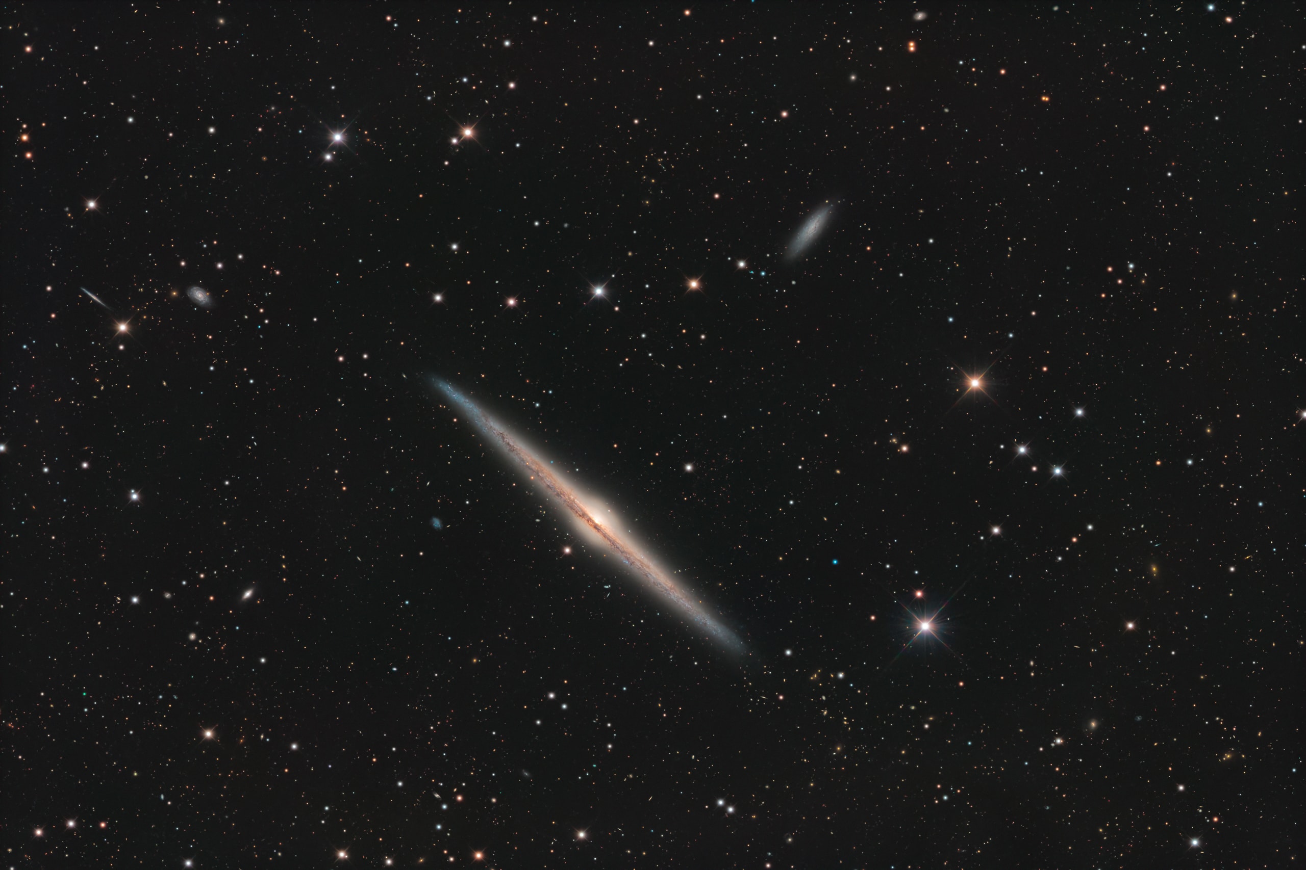 Magnificent spiral galaxy NGC 4565 is viewed edge-on from planet Earth. Also known as the Needle Galaxy for its narrow profile, bright NGC 4565 is a stop on many telescopic tours of the northern sky, in the faint but well-groomed constellation Coma Berenices. This sharp, colorful image reveals the galaxy's boxy, bulging central core cut by obscuring dust lanes that lace NGC 4565's thin galactic plane. NGC 4565 lies around 40 million light-years distant while the spiral galaxy itself spans some 100,000 light-years.  That's about the size of our own Milky Way. Easily spotted with small telescopes, deep sky enthusiasts consider NGC 4565 to be a prominent celestial masterpiece Messier missed.