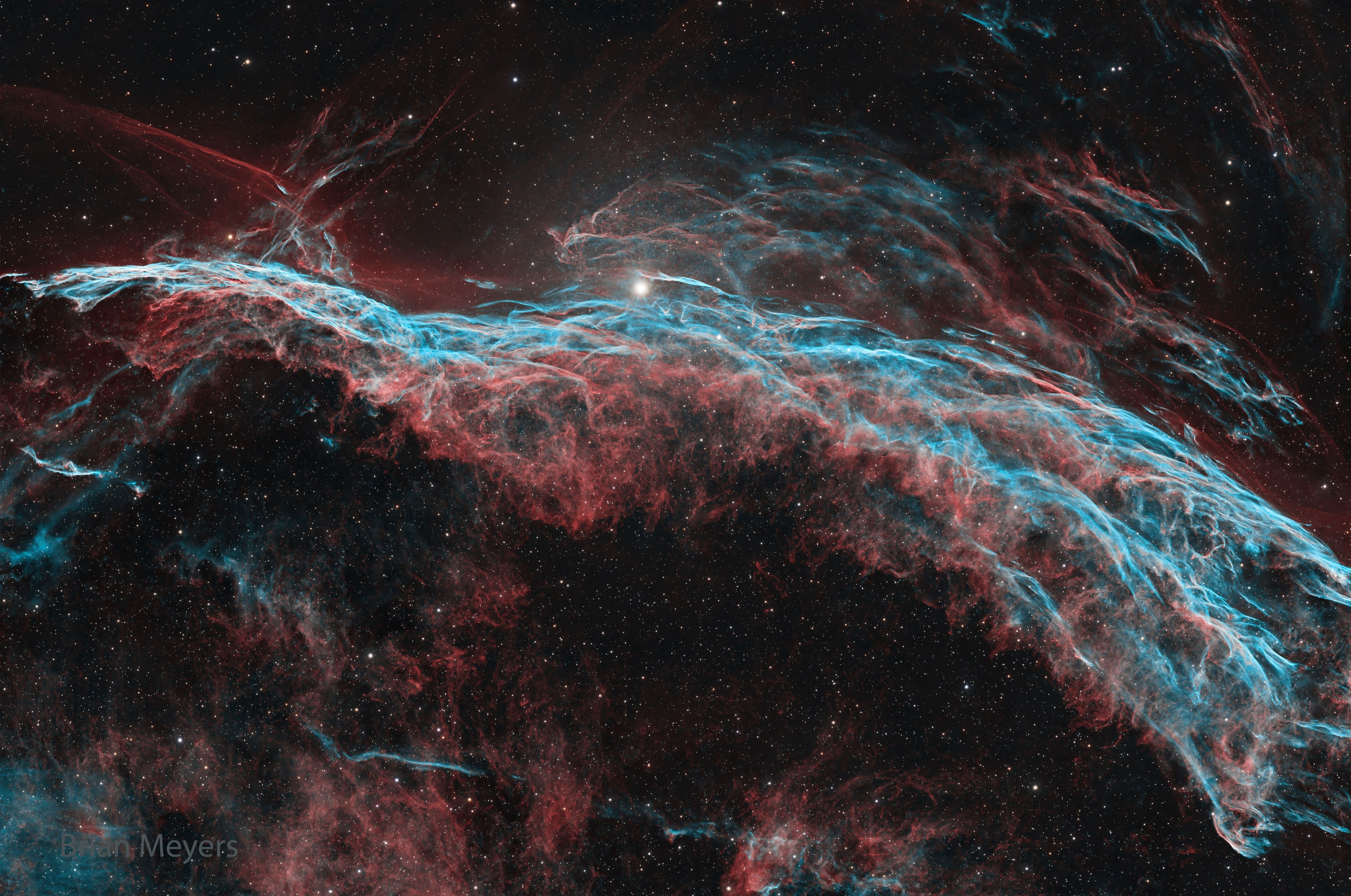 Ten thousand years ago, before the dawn of recorded human history, a new light would suddenly have appeared in the night sky and faded after a few weeks.  Today we know this light was from a supernova, or exploding star, and record the expanding debris cloud as the Veil Nebula, a supernova remnant.  This sharp telescopic view is centered on a western segment of the Veil Nebula cataloged as NGC 6960 but less formally known as the Witch's Broom Nebula.  Blasted out in the cataclysmic explosion, an interstellar shock wave plows through space sweeping up and exciting interstellar material. Imaged with narrow band filters, the glowing filaments are like long ripples in a sheet seen almost edge on, remarkably well separated into atomic hydrogen (red) and oxygen (blue-green) gas. The complete supernova remnant lies about 1400 light-years away towards the constellation Cygnus. This Witch's Broom actually spans about 35 light-years. The bright star in the frame is 52 Cygni, visible with the unaided eye from a dark location but unrelated to the ancient supernova remnant.