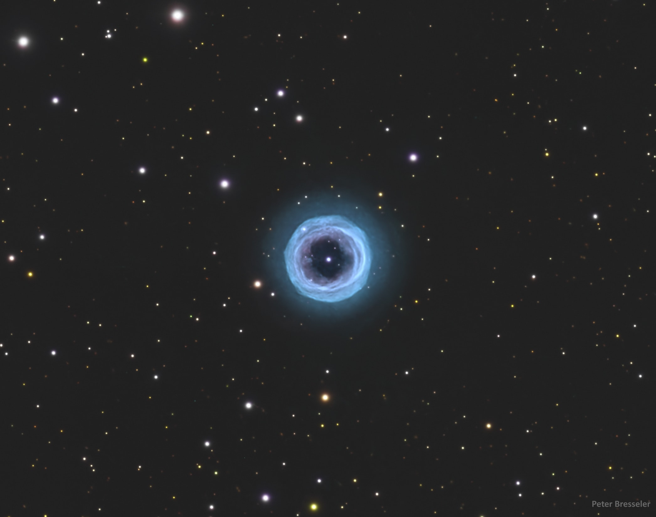 What’s looking back at you isn’t a cosmic eye, but Shapley 1, a beautifully symmetric planetary nebula.  Shapley 1, also known as the Fine Ring Nebula or PLN 329+2.1, bejewels the southern sky constellation of the Carpenter's Square  (Norma).  The nebula is the result of a star near the mass of our Sun running out of fuel and shedding its outer layers.  Glowing oxygen from those expelled layers makes up the circular halo.  The bright central point is actually a binary: a white dwarf, the remaining stellar core after the outer layers are expelled into space, and another star, orbiting each other every 2.9 days.  Shapley 1’s annular shape is due to our top-down view of the system and provides insight into the influence of central stars on planetary nebula structures.