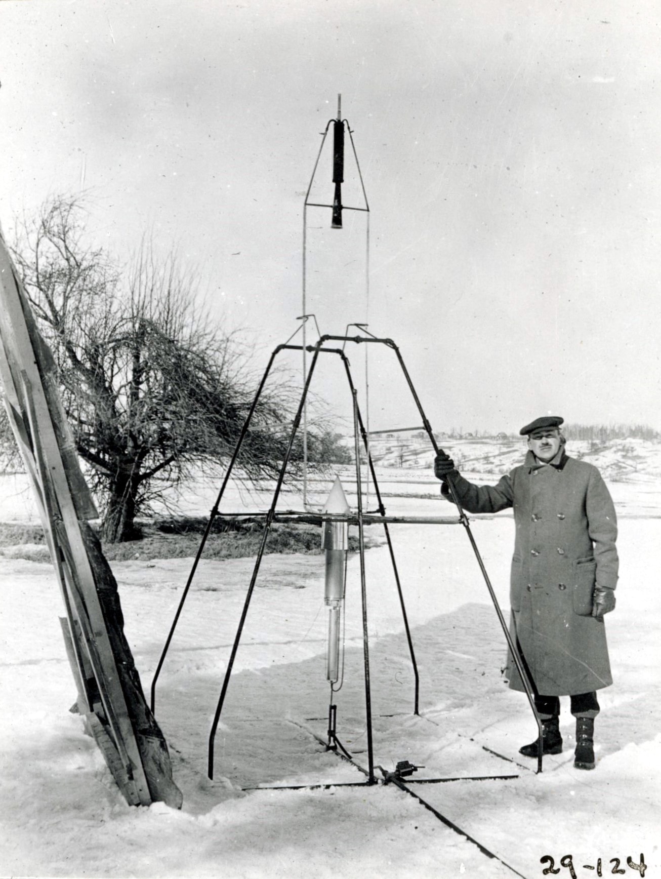 Robert H. Goddard, considered the father of modern rocketry, was born in Worcester Massachusetts in 1882. As a 16 year old, Goddard read H.G. Wells' science fiction classic "War Of The Worlds" and dreamed of space flight. By 1926 he had designed, built, and flown the world's first liquid fuel rocket. Launched 100 years ago, on March 16, 1926 from his aunt Effie's farm in Auburn Massachusetts, the rocket dubbed "Nell", rose to an altitude of 41 feet in a flight that lasted about 2 1/2 seconds. In this posed photo Goddard stands next to the 10 foot tall rocket, holding the launch stand frame. To achieve a stable flight without the need for fins, the rocket's heavy motor was located at the top, fed by lines from liquid oxygen and gasoline fuel tanks at the bottom. Widely recognized as a gifted experimenter and engineering genius, his rockets were many years ahead of their time. Goddard was awarded over 200 patents in rocket technology, most of them after his death in 1945. A liquid fuel rocket constructed on principles developed by Goddard landed humans on the Moon in 1969.