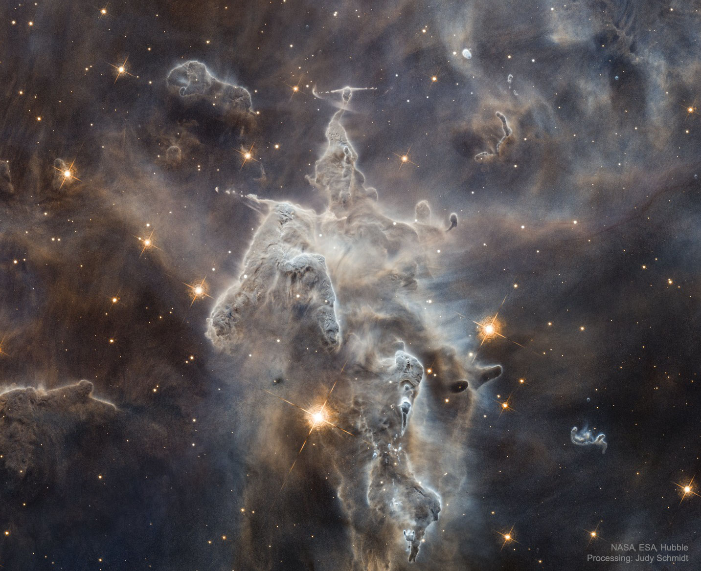 Inside the head of this interstellar monster is a star that is slowly destroying it.  The huge monster, actually an inanimate series of pillars of gas and dust, measures light years in length.  The in-head star is not itself visible through the opaque interstellar dust but is bursting out partly by ejecting opposing beams of energetic particles called Herbig-Haro jets.  Located about 7,500 light years away in the Carina Nebula and known informally as Mystic Mountain, the appearance of these pillars is dominated by dark dust even though they are composed mostly of clear hydrogen gas.  The featured image was taken with the Hubble Space Telescope. All over these pillars, the energetic light and winds from massive newly formed stars are evaporating and dispersing the dusty stellar nurseries in which they formed.  Within a few million years, the head of this giant, as well as most of its body, will have been completely evaporated by internal and surrounding stars.