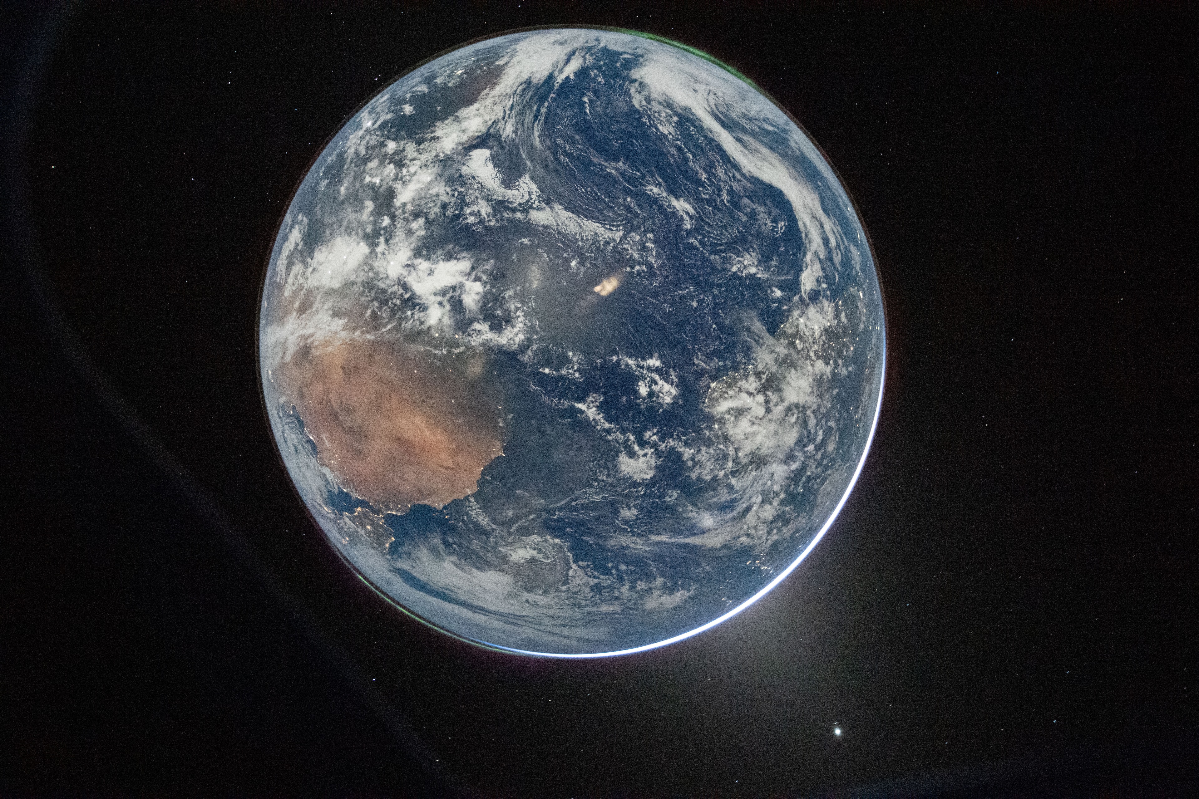 From pole to pole our fair planet is captured in this snapshot from space, an evocative image from a window of the Orion spacecraft Integrity. From the spacecraft's perspective the Sun is moving behind Earth's bright limb along the lower right. Africa and the Iberian peninsula are in view on the pale blue planet's surface, while aurorae crown Earth's south and north poles at top right and bottom left. Commander Reid Wiseman took the historic picture on Artemis II mission flight day 2 (April 2), after the completion of the planned translunar injection burn. That burn boosted the spacecraft out of Earth orbit, sending Integrity and crew on a trajectory that will take them around the Moon and back again. That's a journey humans last made over 50 years ago.