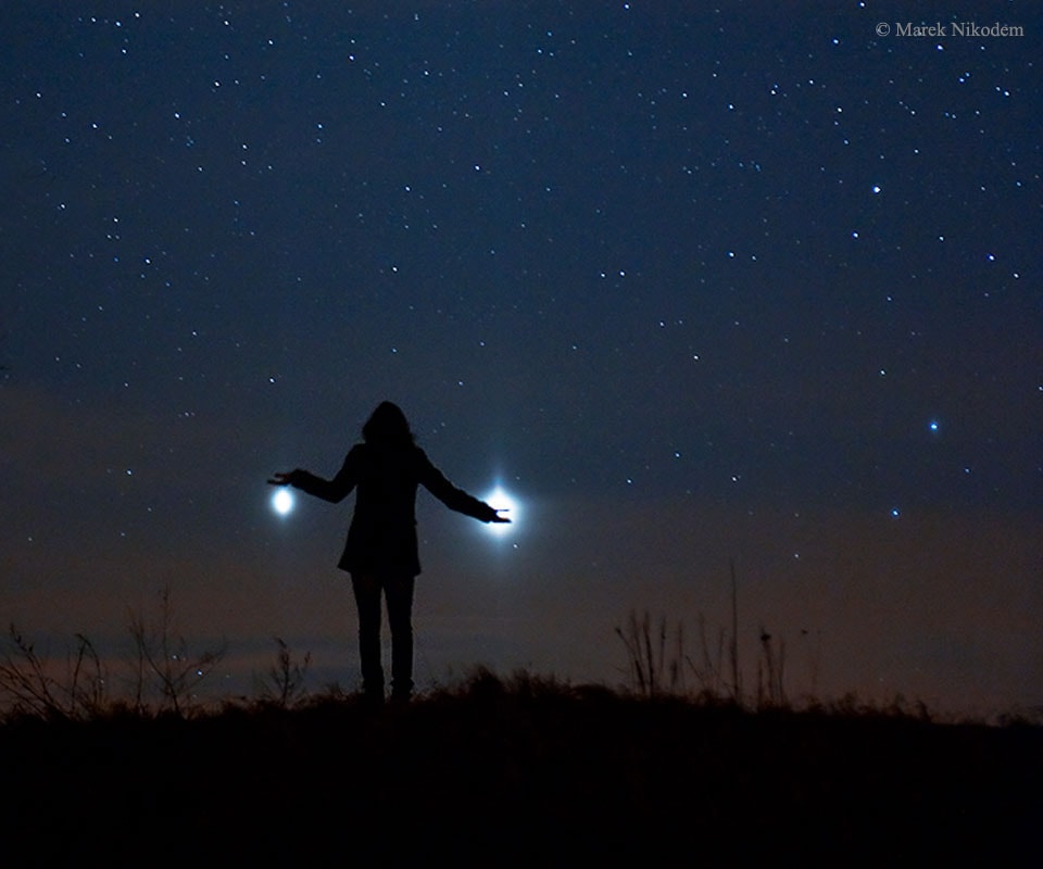 It was visible around the world. The sunset conjunction of Jupiter (left) and Venus (right) in 2012 was visible almost no matter where you lived on Earth.  Anyone on our planet with a clear western horizon at sunset could see them. That year, a creative photographer traveled away from the town lights of Szubin, Poland to photograph  a near closest approach of the two planets. The bright planets were then separated by only  three degrees and his daughter struck a humorous pose. A faint red sunset still glowed in the background. Jupiter and Venus are together again this week after sunset, passing within a degree of each other about two days from today.