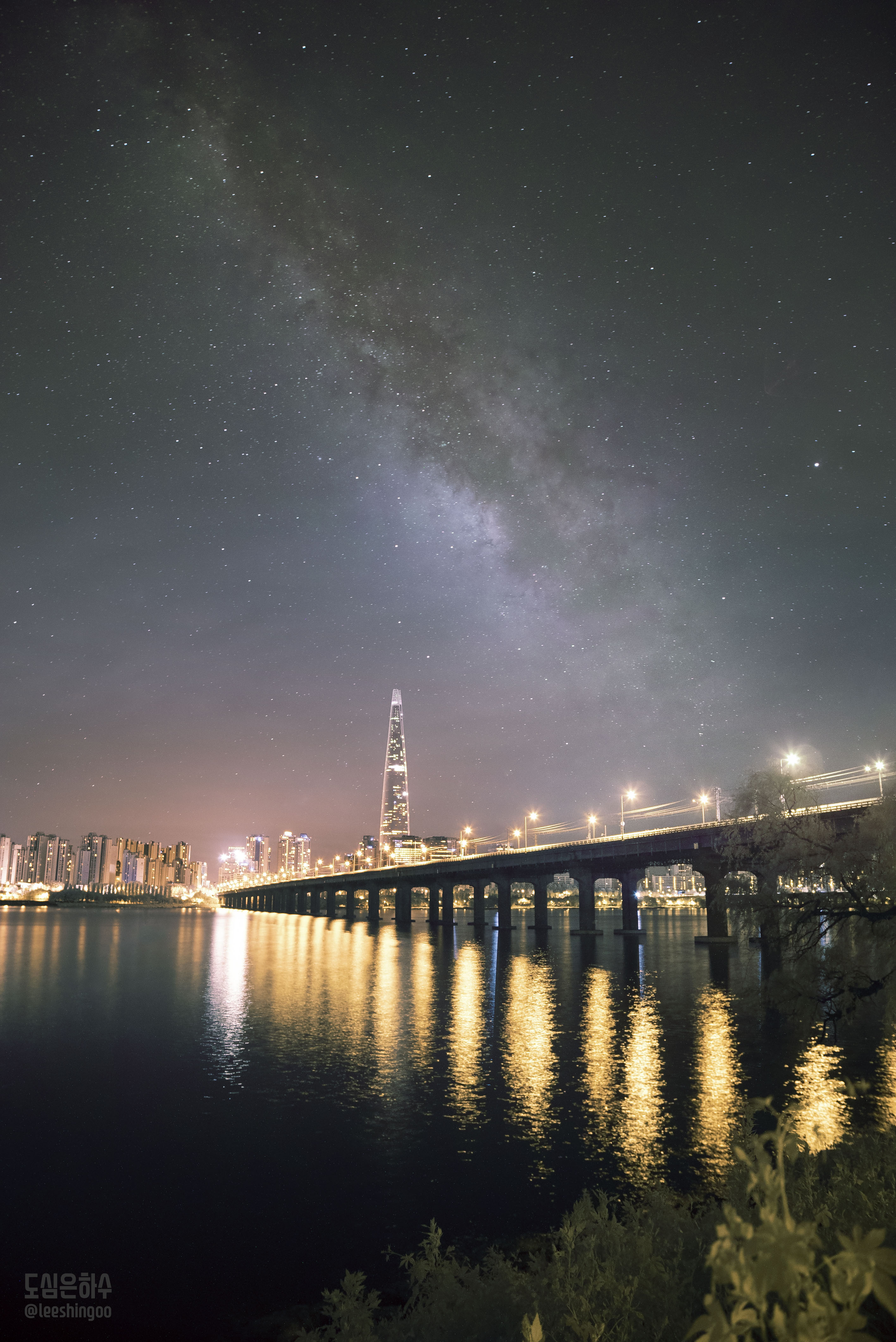 In a cosmic vista you can never see, the Milky Way arcs through the night above Seoul, South Korea. Remarkably, this urban night skyscape reveals our galaxy's faintly luminous central region and dark obscuring dust clouds in spite of the brilliant city lights. To overcome the extreme light pollution of the metropolitan area and record faint cosmic details, an infrared filter was used to capture the night scene in a single exposure. While the filter transmits predominately infrared light, it still passes some visible light to give the scene a natural appearance. The view is from Seoul's Ttukseom Hangang Park, with the Han River and a well lit railway bridge across the foreground. The 123 story Lotte World Tower looms in the distance, the tallest building in South Korea.