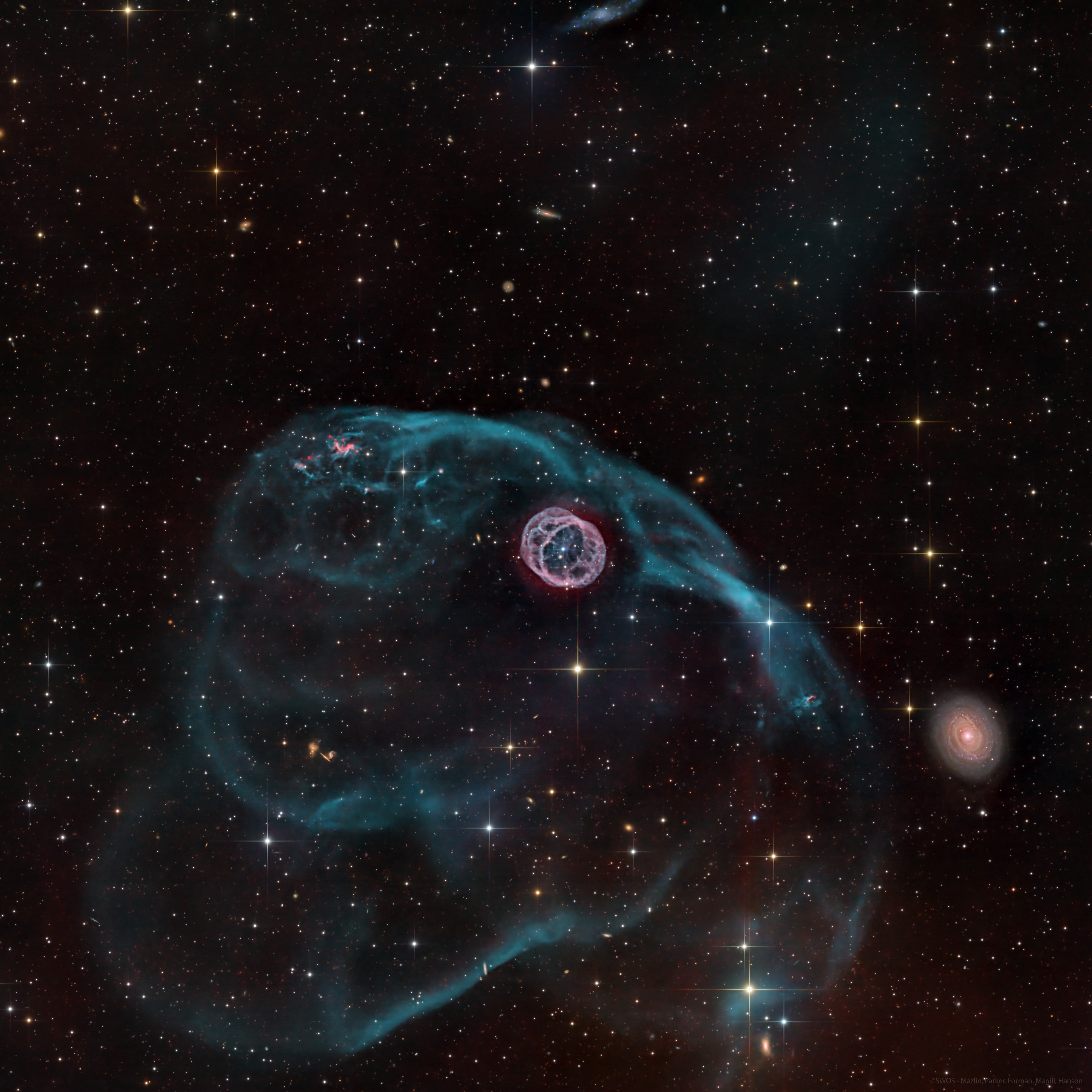 How did a hamster wheel get into space? The Hamster Wheel Nebula (Longmore 8) was discovered by Andrew Longmore in 1976 as a part of a larger survey of the southern sky. This survey employed several improvements in photographic technology, including the use of highly sensitive film, to capture deeper and fainter objects on plates that were examined by eye and catalogued. The featured image, taken at Observatorio El Sauce in Chile, depicts an intricate wheel structure of glowing hydrogen that was thrown out into space by a dying star and ionized by the leftover white dwarf. This structure was barely visible on the original plate, emphasizing the power of modern telescopes and cameras. Two opposing clumps of red hydrogen gas encased in the blue veil of ionized oxygen hint at the presence of a companion to the bright white dwarf at the wheel’s center!