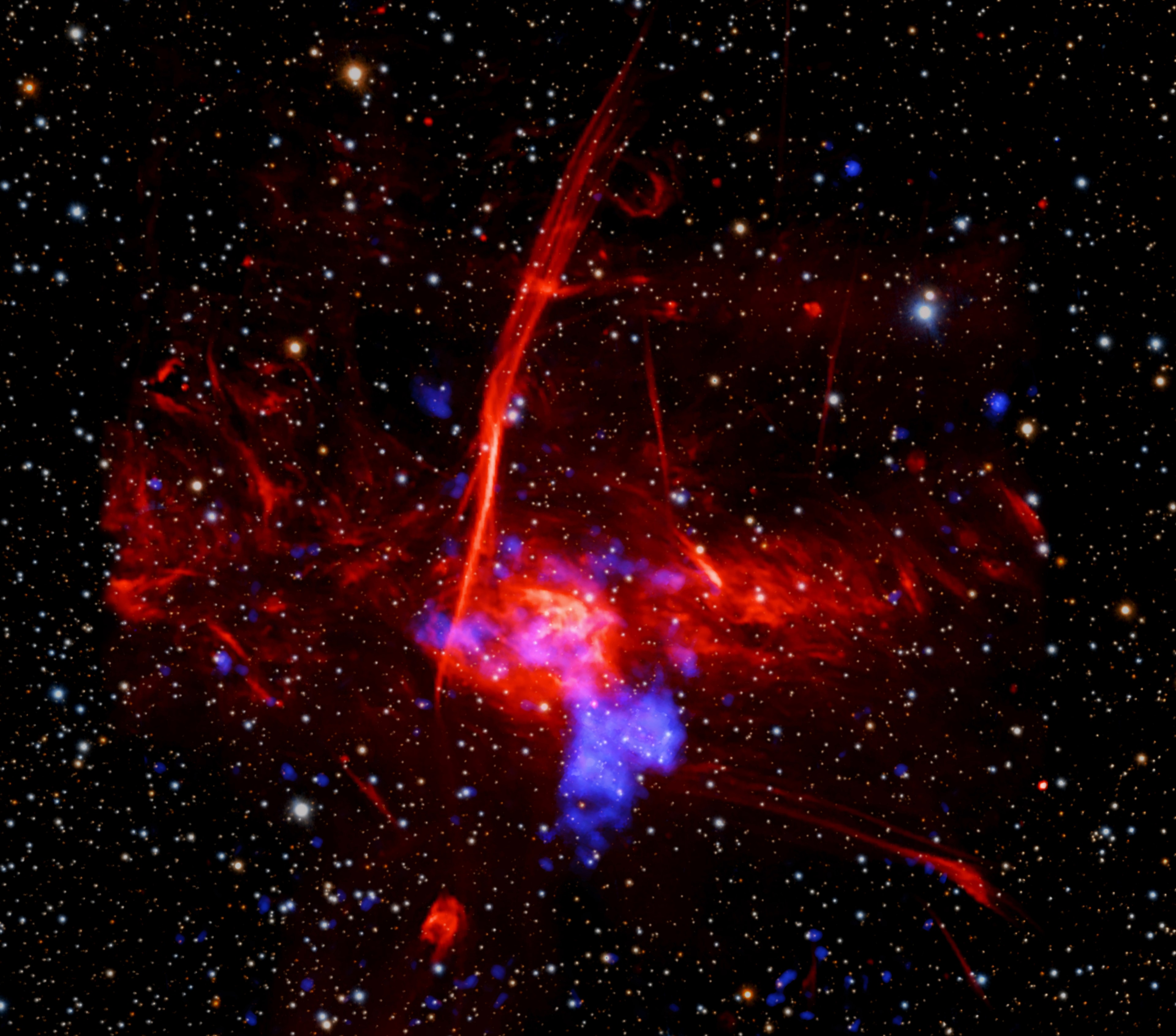 Do you see that blue blob to the lower right of the image center?   Astronomers think that it shows where a massive star exploded as a supernova whose light reached Earth 1,700 years ago.   The image combines optical data from the PanSTARRS telescopes in Hawaii (background stars in red, green, and blue), radio from the MeerKAT telescope in South Africa (large red cloud) and X-rays from NASA's Chandra X-ray Observatory and ESA’s XMM-Newton (shown in blue).   The large cloud is a star forming region called Sagittarius C, which is approximately 50 light-years in extent and about 26,000 light-years from Earth.   It is located only about 260 light-years from the supermassive black hole in the center of the Galaxy (off to the left of the image).   If the blue blob is confirmed to be a supernova remnant, it would be one of the closest ever discovered to the Galactic Center.   In this dense region, the deaths of massive stars are connected to the birth of new stars through gas and magnetic fields in a complex way.