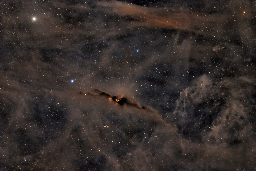 This Cosmic Bat wishes you a happy Summerween! This mid-year celebration of Halloween transcends hemispheres, even though summer in the Northern hemisphere is winter in the South. Contrary to its eery aura, the Cosmic Bat Nebula (LDN 43), not to be confused with the Bat Nebula (NGC 6995), is a vibrant birthplace for stars. A bit of young starlight peeks through the dense clouds of gas and dust that make up the Cosmic Bat’s 12 lightyear wingspan. The ultraviolet light from the young stars energizes the nebula’s hydrogen gas, causing it to glow an ominous red. The jet of glowing hydrogen gas emerging from the bat’s head hints at the star formation hidden within.