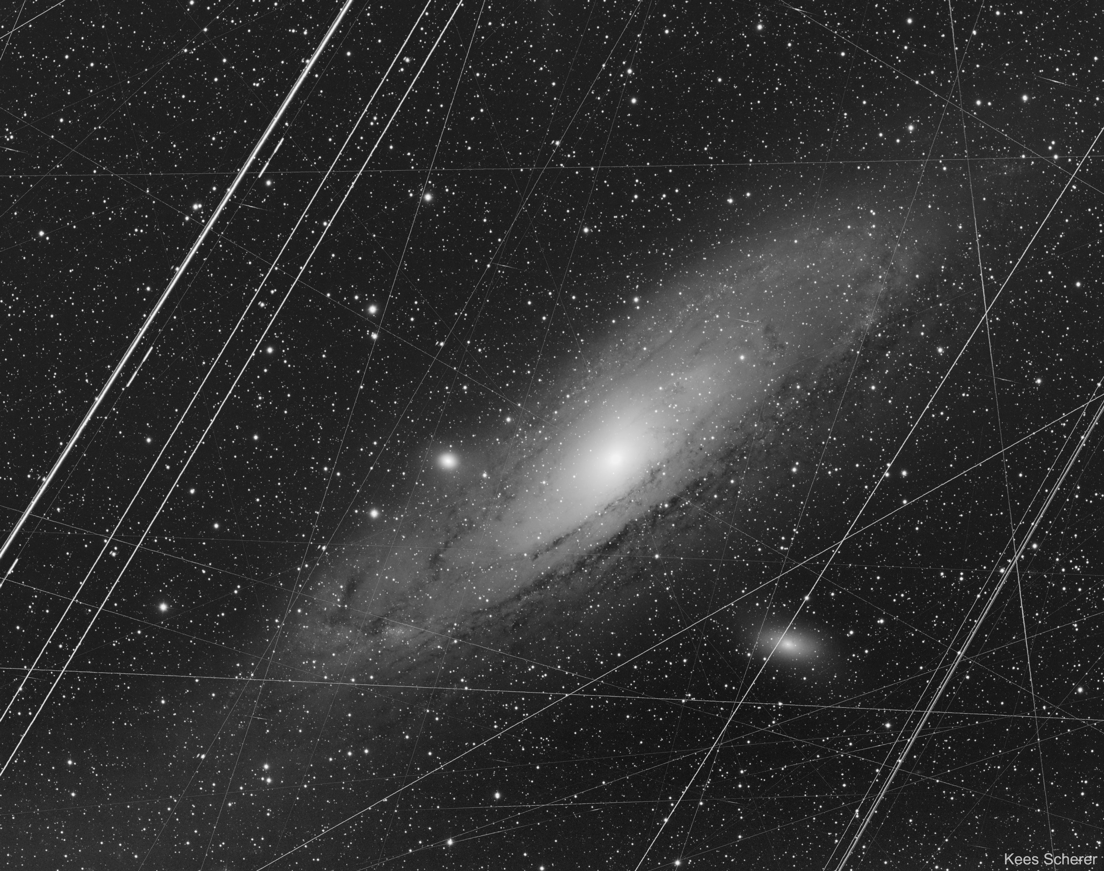 What does the Andromeda galaxy really look like? The featured image shows how our Milky Way Galaxy's closest major galactic neighbor really appears in a long exposure through Earth's busy skies and with a digital camera that introduces normal imperfections.  The picture is a stack of 223 images, each a 300 second exposure, taken from a garden observatory in Portugal during 2019.  Obvious image deficiencies include bright parallel airplane trails, long and continuous satellite trails, short cosmic ray streaks, and bad pixels.  These imperfections were actually not removed with Photoshop specifically, but rather greatly reduced with a series of computer software packages that included Astro Pixel Processor, DeepSkyStacker, and PixInsight.  All of this work was done not to deceive you with a digital fantasy that has little to do with the real likeness of the Andromeda galaxy (M31), but to minimize Earthly artifacts that have nothing to do with the distant galaxy and so better recreate what M31 really does look like.   APOD's email for image submissions has changed. Please see: APOD Submissions APOD's main NASA site is moving: From apod.nasa.gov to science.nasa.gov/apod