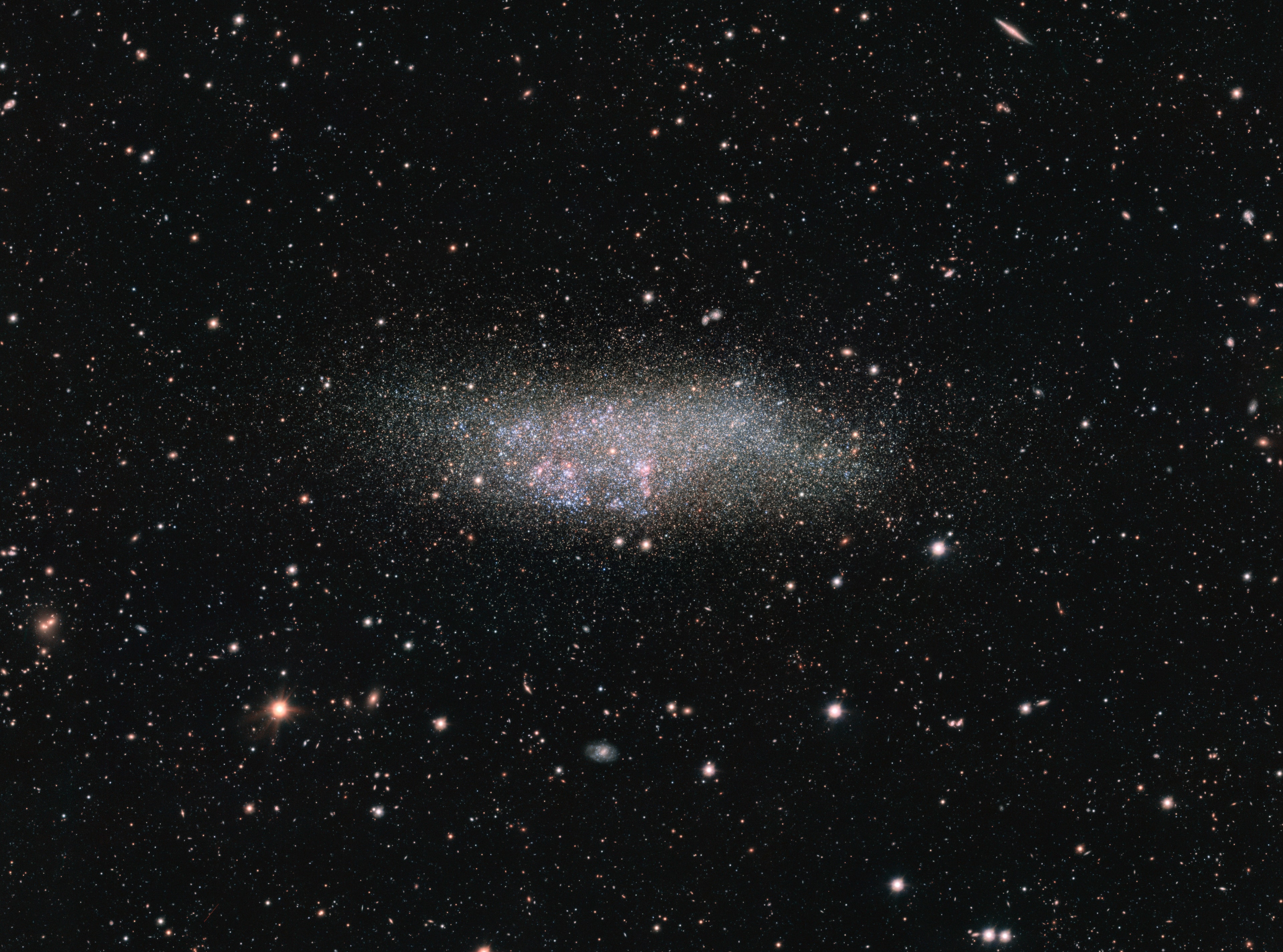 Named for the three astronomers instrumental in its discovery and identification, Wolf - Lundmark - Melotte (WLM) is a lonely dwarf galaxy. Seen toward the mostly southern constellation Cetus, about 3 million light-years from the Milky Way, it is one of the most remote members of our local galaxy group. In fact, it may never have interacted with any other local group galaxy. Still, telltale pinkish star forming regions and hot, young, bluish stars speckle the isolated island universe. Older, cool yellowish stars fade into the small galaxy's halo, extending about 8,000 light-years across. This sharp portrait of WLM was captured by the 268-megapixel OmegaCAM widefield imager and survey telescope at ESO's Paranal Observatory.