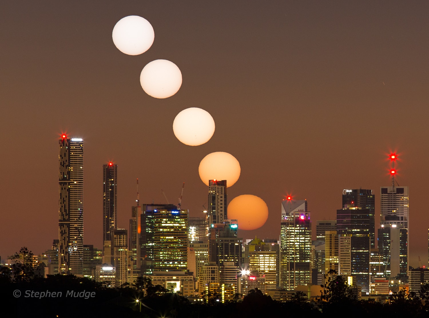 On July 3rd, planet Earth reached aphelion, the farthest point in its elliptical orbit around the Sun. Each year, this day of the most distant Sun happens to occur during winter in the southern hemisphere. That's where this aphelion sunrise from 2015 was captured in a time series composite against the skyline of Brisbane, Australia. Of course, seasons for our fair planet are not determined by distance to the Sun, but by the tilt of Earth's rotational axis with respect to the ecliptic, the plane of its orbit. Fondly known as the obliquity of the ecliptic, the angle of the tilt is about 23.4 degrees from perpendicular to the orbital plane. So the most distant sunrise occurs during northern summer, when the planet's north pole is tilted toward the Sun and the north enjoys longer, warmer days.