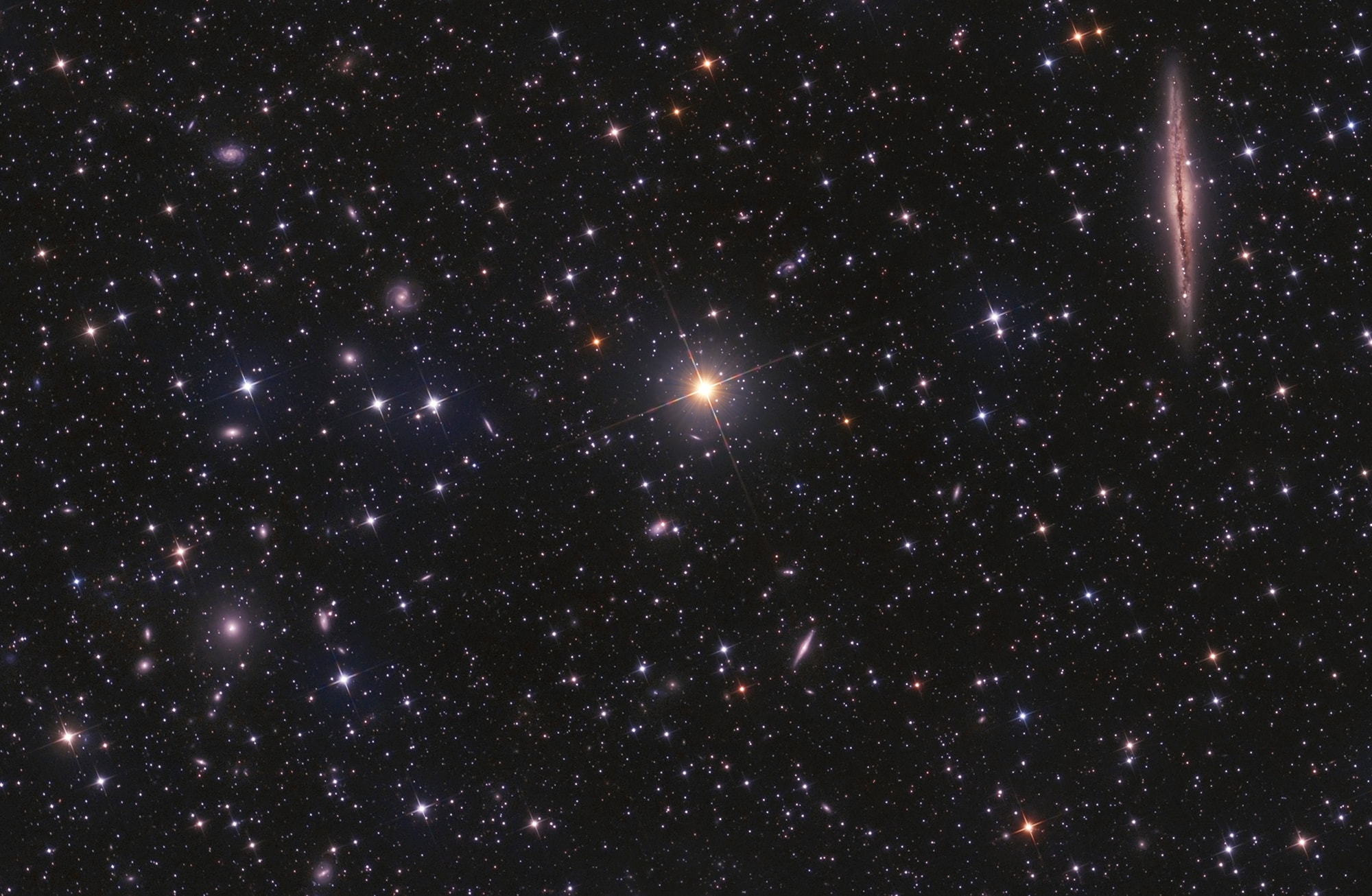 Distant galaxies lie beyond a foreground of spiky Milky Way stars in this telescopic field of view. Centered on yellowish star HD 14771, the scene spans about 1 degree on the sky toward the northern constellation Andromeda. At top right is large spiral galaxy NGC 891, 100 thousand light-years across and seen almost exactly edge-on. About 30 million light-years distant, NGC 891 looks a lot like our own Milky Way with a flattened, thin, galactic disk. Its disk and central bulge are cut along the middle by dark, obscuring dust clouds. Scattered toward the lower left are members of galaxy cluster Abell 347. Nearly 240 million light-years away, Abell 347 shows off its own large galaxies in the sharp image. They are similar to NGC 891 in physical size but located almost 8 times farther away, so Abell 347 galaxies have roughly one eighth the apparent size of NGC 891.