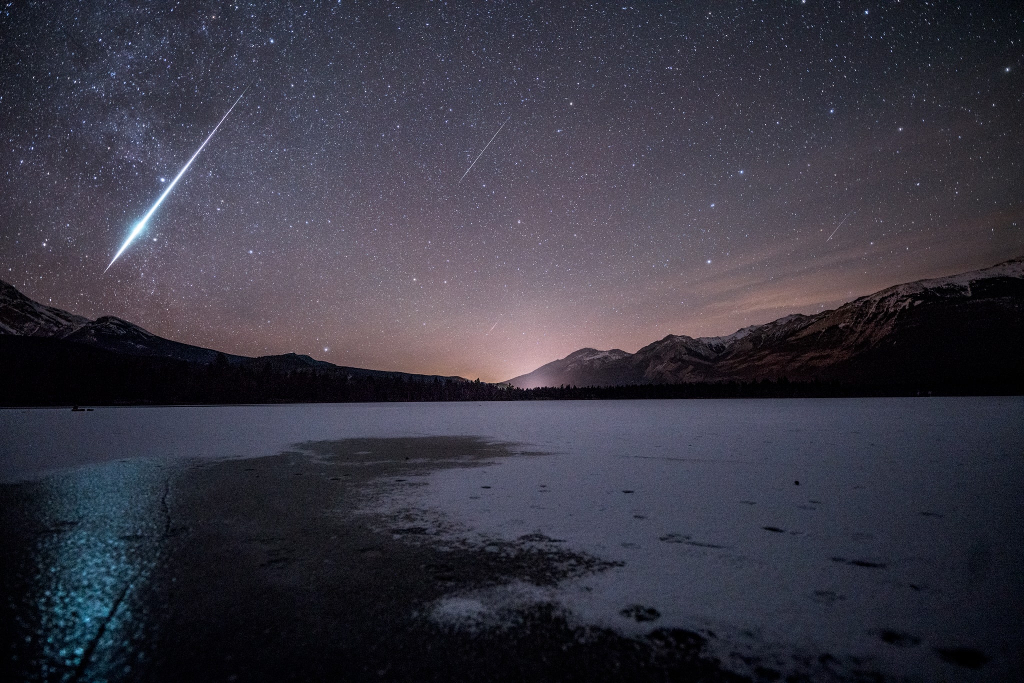 Four Geminids flash through northern skies in this wintry night skyscape. The bright fireball and 3 fainter meteors were captured in a single 10 second exposure, near the peak of December's Geminid meteor shower. Reflecting the fireball's greenish light, a partially frozen Lake Edith in Alberta Canada's Jasper National Park lies in the foreground, with the Canadian Rocky Mountains ranging along the northern horizon. Of course, the glacial lake is cold even in summer. But photographer Jack Fusco reports that he experienced -9 degree C temperatures that night while enjoying one of the most active meteor showers he's ever seen.