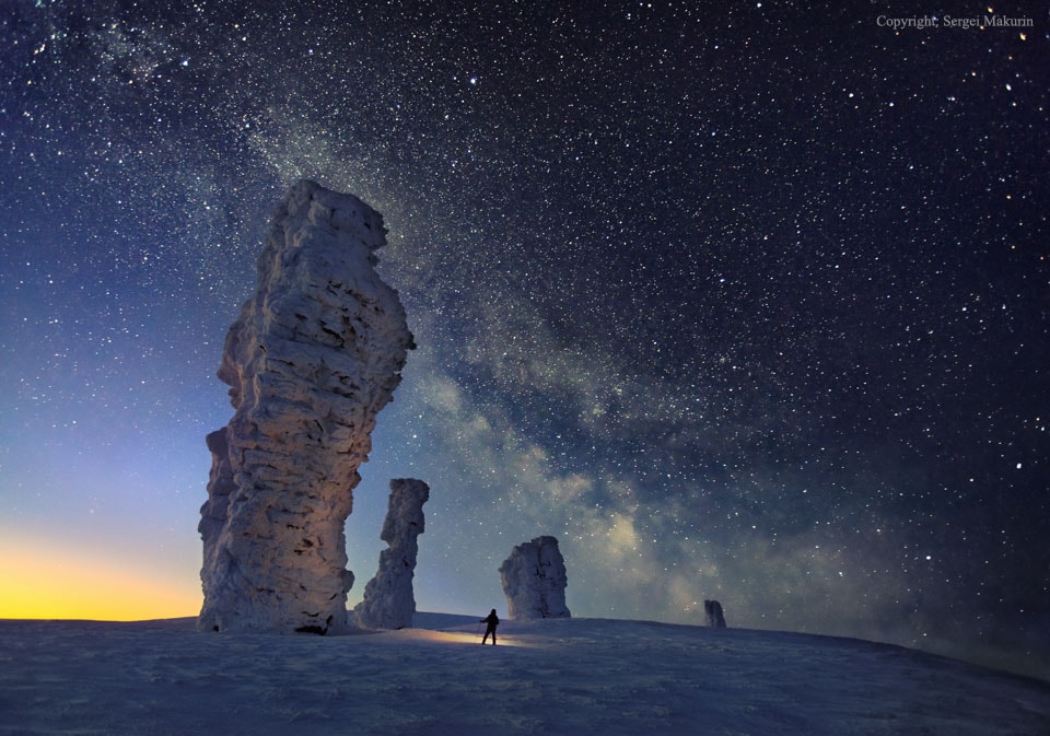 You may have heard of the Seven Sisters in the sky, but have you heard about the Seven Strong Men on the ground? Located just west of the Ural Mountains, the unusual Manpupuner rock formations are one of the Seven Wonders of Russia. How these ancient 40-meter high pillars formed is yet unknown. The persistent photographer of this featured image battled rough terrain and uncooperative weather to capture these rugged stone towers in winter at night, being finally successful in February of 2014. Utilizing the camera's time delay feature, the photographer holds a flashlight in the foreground near one of the snow-covered pillars. High above, millions of stars shine down, while the band of our Milky Way Galaxy crosses diagonally down from the upper left.