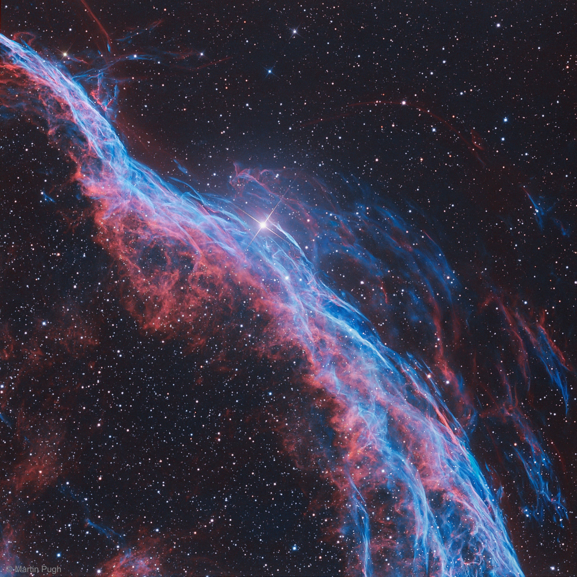 Ten thousand years ago, before the dawn of recorded human history, a new light would have suddenly have appeared in the night sky and faded after a few weeks. Today we know this light was from a supernova, or exploding star, and record the expanding debris cloud as the Veil Nebula, a supernova remnant. This sharp telescopic view is centered on a western segment of the Veil Nebula cataloged as NGC 6960 but less formally known as the Witch's Broom Nebula. Blasted out in the cataclysmic explosion, the interstellar shock wave plows through space sweeping up and exciting interstellar material. Imaged with narrow band filters, the glowing filaments are like long ripples in a sheet seen almost edge on, remarkably well separated into atomic hydrogen (red) and oxygen (blue-green) gas. The complete supernova remnant lies about 1400 light-years away towards the constellation Cygnus. This Witch's Broom actually spans about 35 light-years. The bright star in the frame is 52 Cygni, visible with the unaided eye from a dark location but unrelated to the ancient supernova remnant.