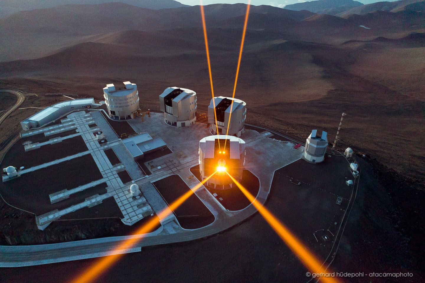 Dodging powerful laser beams, a drone captured this stunning aerial view. The confrontation took place above the 8.2 meter diameter Very Large Telescopes of the Paranal Observatory on planet Earth. Firing during a test of the observatory's 4 Laser Guide Star Facility, the lasers are ultimately battling against the blurring effect of atmospheric turbulence by creating artificial guide stars. The guide stars are actually emission from laser excited sodium atoms at high altitudes within the telescopic field of view. Guide star image fluctuations are used in real-time to correct for atmospheric blurring by controlling a deformable mirror in the telescope's optical path. Known as adaptive optics, the technique can produce images at the diffraction limit of the telescope. That's the same sharpness you would get if the telescope were in space.