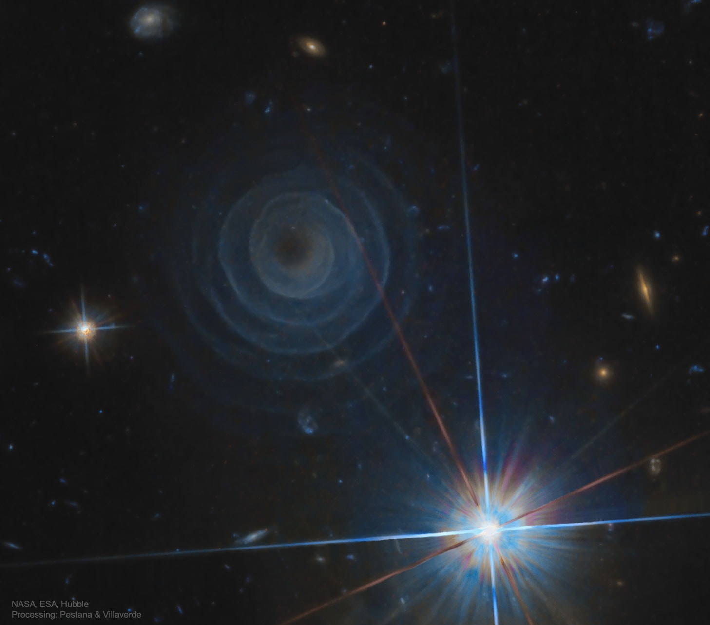 What created the strange spiral structure on the upper left? No one is sure, although it is likely related to a star in a binary star system entering the planetary nebula phase, when its outer atmosphere is ejected. The huge spiral spans about a third of a light year across and, winding four or five complete turns, has a regularity that is without precedent. Given the expansion rate of the spiral gas, a new layer must appear about every 800 years, a close match to the time it takes for the two stars to orbit each other. The star system that created it is most commonly known as LL Pegasi, but also AFGL 3068. The unusual structure itself has been cataloged as IRAS 23166+1655. The featured image was taken in near-infrared light by the Hubble Space Telescope. Why the spiral glows is itself a mystery, with a leading hypothesis being illumination by light reflected from nearby stars.