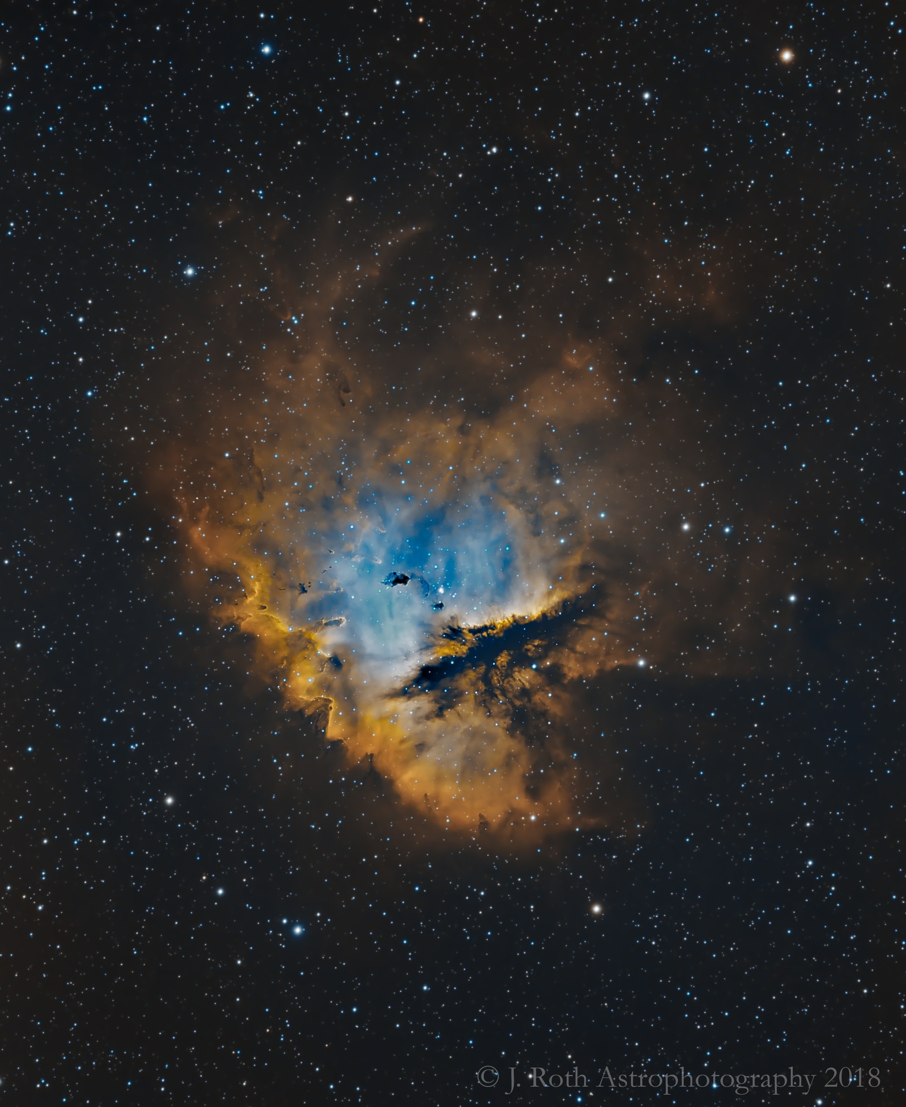 Look through the cosmic cloud cataloged as NGC 281 and you might miss the stars of open cluster IC 1590. Still, formed within the nebula that cluster's young, massive stars ultimately power the pervasive nebular glow. The eye-catching shapes looming in this portrait of NGC 281 are sculpted dusty columns and dense Bok globules seen in silhouette, eroded by intense, energetic winds and radiation from the hot cluster stars. If they survive long enough, the dusty structures could also be sites of future star formation. Playfully called the Pacman Nebula because of its overall shape, NGC 281 is about 10,000 light-years away in the constellation Cassiopeia. This sharp composite image was made through narrow-band filters. It combines emission from the nebula's hydrogen and oxygen atoms to synthesize red, green, and blue colors. The scene spans well over 80 light-years at the estimated distance of NGC 281.