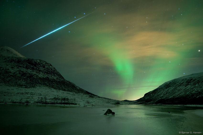 Some night skies are serene and passive -- others shimmer and flash. The later, in the form of auroras and meteors, haunted skies over the island of Kvaløya, near Tromsø Norway on 2009 December 13. This 30 second long exposure records a shimmering auroral glow gently lighting the wintery coastal scene. A study in contrasts, the image also captures the sudden flash of a fireball meteor from the excellent Geminid meteor shower of 2009. Streaking past familiar stars in the handle of the Big Dipper, the trail points back toward the constellation Gemini, off the top of the view. Both auroras and meteors occur in Earth's upper atmosphere at altitudes of 100 kilometers or so, but aurora caused by energetic charged particles from the magnetosphere, while meteors are trails of cosmic dust. Nine years after this photograph was taken, toward the end of this week, the yearly 2018 Geminids meteor shower will peak again, although this time their flashes will compete with the din of a half-lit first-quarter moon during the first half of the night. Free Download: 2019 APOD Calendar