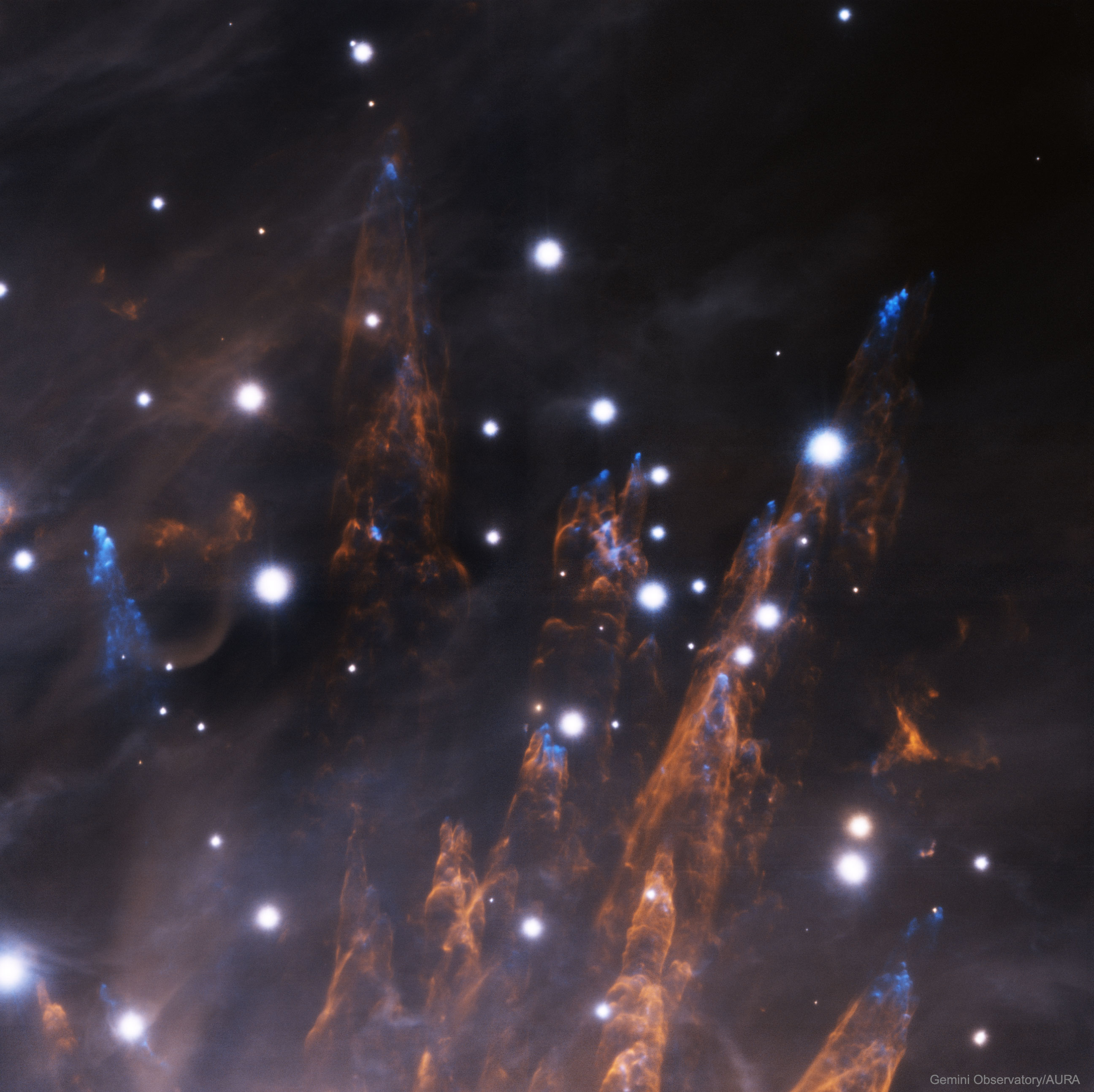 Why are bullets of gas shooting out of the Orion Nebula? Nobody is yet sure. First discovered in 1983, each bullet is actually about the size of our Solar System, and moving at about 400 km/sec from a central source dubbed IRc2. The age of the bullets, which can be found from their speed and distance from IRc2, is very young -- typically less than 1,000 years. As the bullets expand out the top of the Kleinmann-Low section of the Orion Nebula, a small percentage of iron gas causes the tip of each bullet to glow blue, while each bullet leaves a tubular pillar that glows by the light of heated hydrogen gas. The detailed image was created using the 8.1 meter Gemini South telescope in Chile with an adaptive optics system (GeMS). GeMS uses five laser generated guide stars to help compensate for the blurring effects of planet Earth's atmosphere.