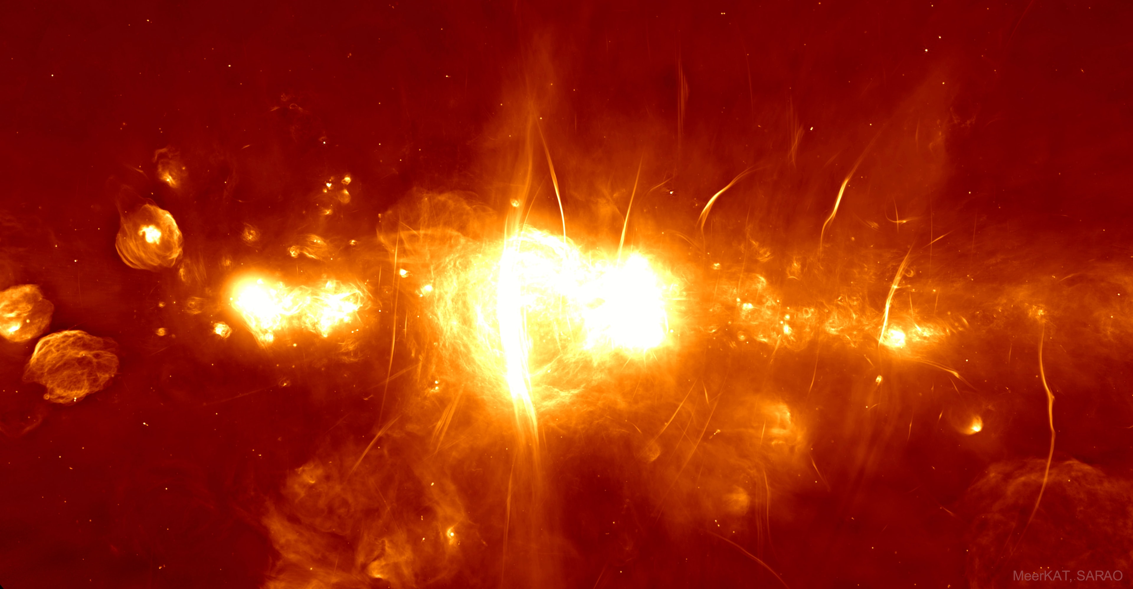 What's happening at the center of our galaxy? It's hard to tell with optical telescopes since visible light is blocked by intervening interstellar dust. In other bands of light, though, such as radio, the galactic center can be imaged and shows itself to be quite an interesting and active place. The featured picture shows the inaugural image of the MeerKAT array of 64 radio dishes just completed in South Africa. Spanning four times the angular size of the Moon (2 degrees), the image is impressively vast, deep, and detailed. Many known sources are shown in clear detail, including many with a prefix of Sgr, since the Galactic Center is in the direction of the constellation Sagittarius. In our Galaxy's Center lies Sgr A, found here just to the right of the image center, which houses the Milky Way's central supermassive black hole. Other sources in the image are not as well understood, including the Arc, just to the left of Sgr A, and numerous filamentary threads. Goals for MeerKAT include searching for radio emission from neutral hydrogen emitted in a much younger universe and brief but distant radio flashes.