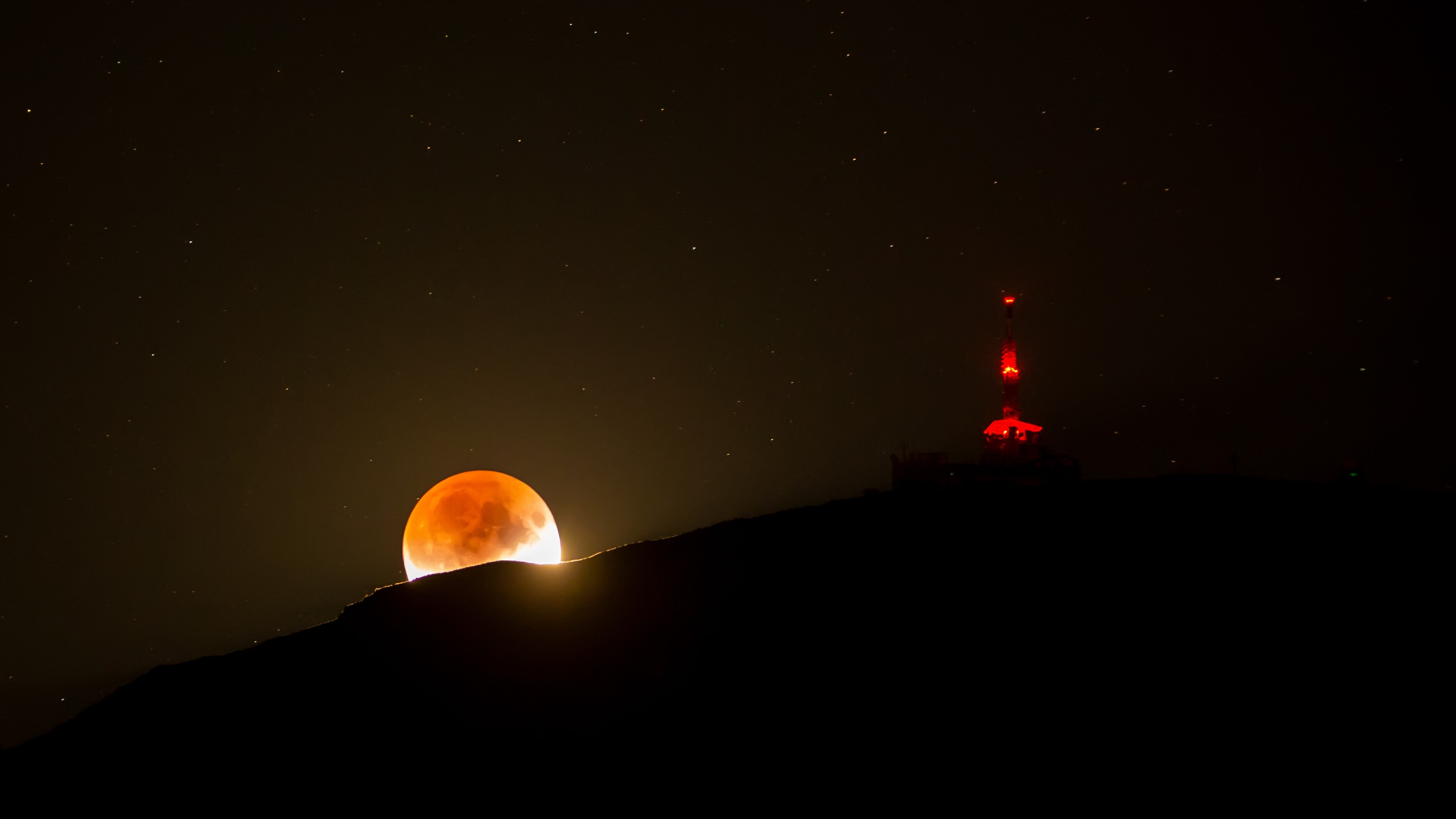 On July 16 the Moon celebrated the 50th anniversary of the launch of Apollo 11 with a lunar eclipse visible from much of planet Earth. In this view part of the lunar disk is immersed in Earth's dark, reddened umbral shadow. Near the maximum eclipse phase, it just touches down along a mountain ridge. The rugged Tyrolean nightscape was recorded after moonrise south of Innsbruck, Austria with a dramatically lit communication tower along the ridgeline. Of course eclipses rarely travel alone. This partial lunar eclipse was at the Full Moon following July 2nd's New Moon and total eclipse of the Sun.