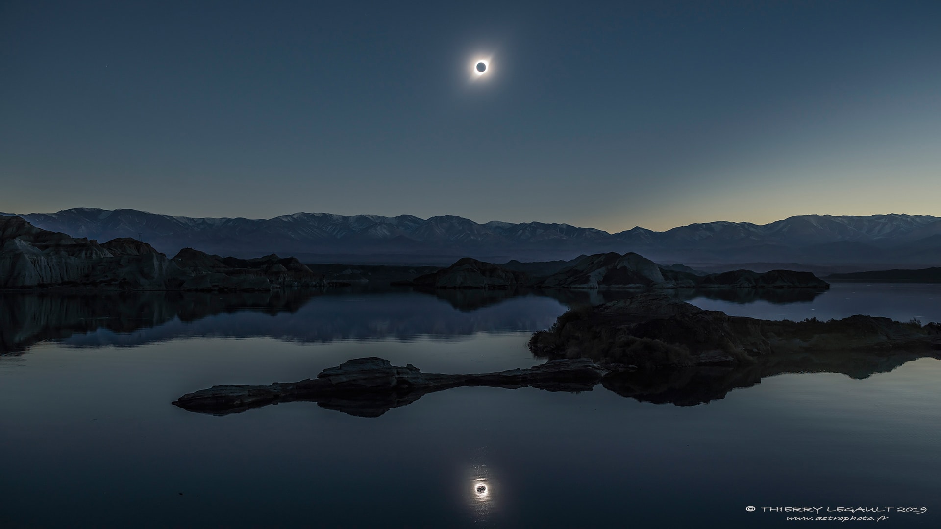 If you saw a total solar eclipse, would you do a double-take? One astrophotographer did just that -- but it took a lake and a bit of planning. Realizing that the eclipse would be low on the horizon, he looked for a suitable place along the thin swath of South America that would see, for a few minutes, the Moon completely block the Sun, both directly and in reflection. The day before totality, he visited an Argentine lake called La Cuesta Del Viento (The Slope of the Wind) and, despite its name, found so little wind that the lake looked like a mirror. Perfect. Returning the day of the eclipse, though, there was a strong breeze churning up the water -- enough to ruin the eclipse reflection shot. Despair. But wait! Strangely, about an hour before totality, the wind died down. This calmness may have been related to the eclipse itself, because eclipsed ground heats the air less and reduces the amount rising warm air -- which can dampen and even change the wind direction. The eclipse came, his tripod and camera were ready, and so was the lake. The featured image of this double-eclipse came from a single exposure lasting just one fifteenth of a second. Soon after totality, the winds returned and the water again became choppy. No matter -- this double-image of the 2019 July total solar eclipse had been captured forever.