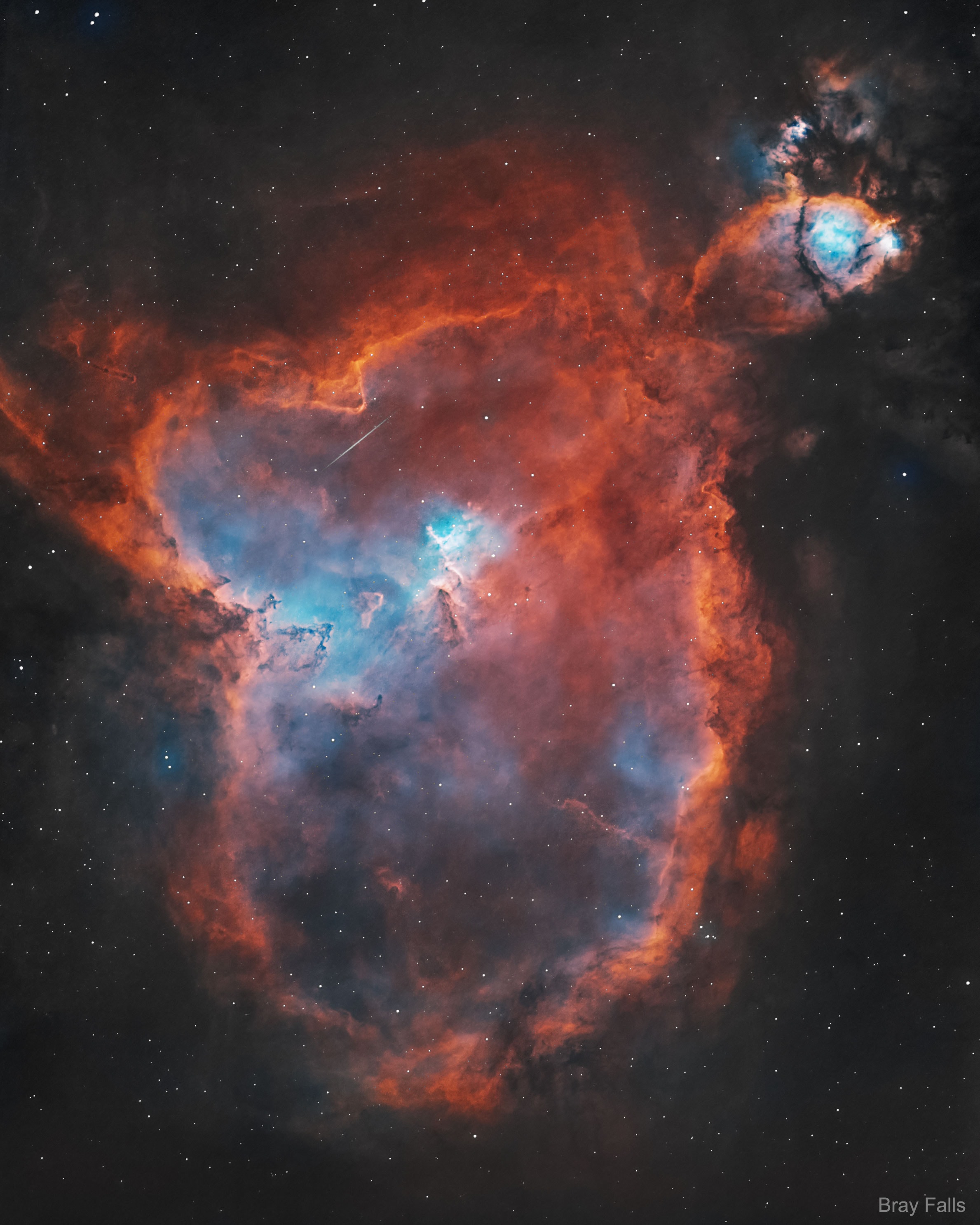 What energizes the Heart Nebula? First, the large emission nebula dubbed IC 1805 looks, in whole, like a human heart. The nebula glows brightly in red light emitted by its most prominent element: hydrogen. The red glow and the larger shape are all powered by a small group of stars near the nebula's center. In the center of the Heart Nebula are young stars from the open star cluster Melotte 15 that are eroding away several picturesque dust pillars with their energetic light and winds. The open cluster of stars contains a few bright stars nearly 50 times the mass of our Sun, many dim stars only a fraction of the mass of our Sun, and an absent microquasar that was expelled millions of years ago. The Heart Nebula is located about 7,500 light years away toward the constellation of Cassiopeia. Coincidentally, a small meteor was captured in the foreground during imaging and is visible above the dust pillars. At the top right is the companion Fishhead Nebula.