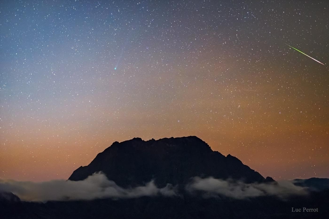 The pre-dawn hours of May 3rd were moonless as grains of cosmic dust streaked through southern skies above Reunion Island. Swept up as planet Earth plowed through dusty debris streams left behind periodic Comet 1/P Halley, the annual meteor shower is known as the Eta Aquarids. This inspired exposure captures a bright aquarid meteor flashing left to right over a sea of clouds. The meteor streak points back to the shower's radiant in the constellation Aquarius, well above the eastern horizon and off the top of the frame. Known for speed Eta Aquarid meteors move fast, entering the atmosphere at about 66 kilometers per second, visible at altitudes of 100 kilometers or so. Then about 6 light-minutes from Earth, the pale greenish coma and long tail of Comet C/2020 F8 SWAN were not to be left out of the celestial scene, posing above the volcanic peaks left of center. Now in the northern sky's morning twilight near the eastern horizon Comet SWAN has not become as bright as anticipated though. This first time comet made its closest approach to planet Earth only two days ago and reaches perihelion on May 27.