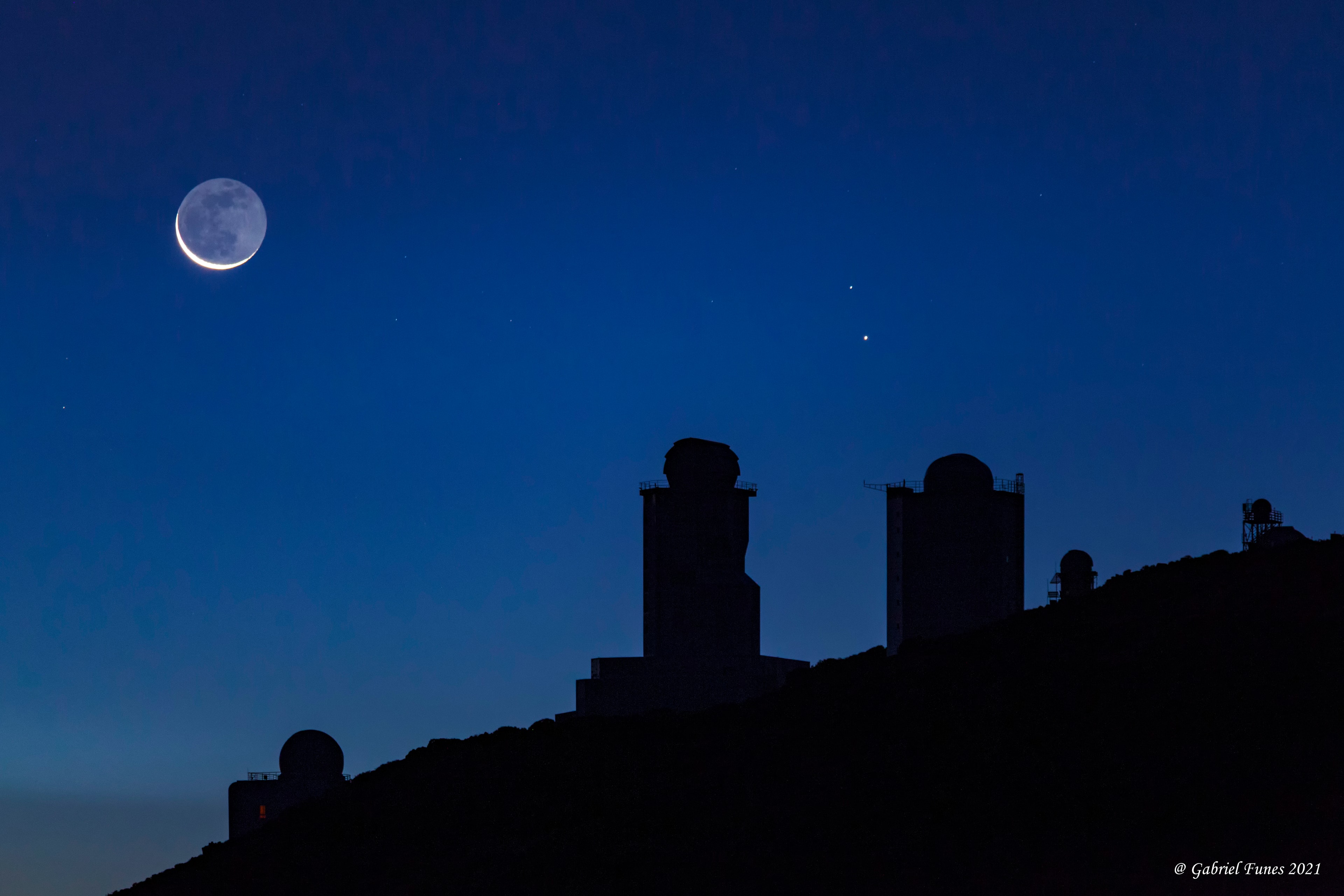 On July 8th early morning risers saw Mercury near an old Moon low on the eastern horizon. On that date bright planet, faint glow of lunar night side, and sunlit crescent were captured in this predawn skyscape from Tenerife's Teide National Park in the Canary Islands. Never far from the Sun in planet Earth's sky, the fleeting inner planet shines near its brightest in the morning twilight scene. Mercury lies just below the zeta star of the constellation Taurus, Zeta Tauri, near the tip of the celestial bull's horn. Of course the Moon's ashen glow is earthshine, earthlight reflected from the Moon's night side. A description of earthshine, in terms of sunlight reflected by Earth's oceans illuminating the Moon's dark surface, was written over 500 years ago by Leonardo da Vinci. Waiting for the coming dawn in the foreground are the Teide Observatory's sentinels of the Sun, also known as (large domes left to right) the THEMIS, VTT, and GREGOR solar telescopes.