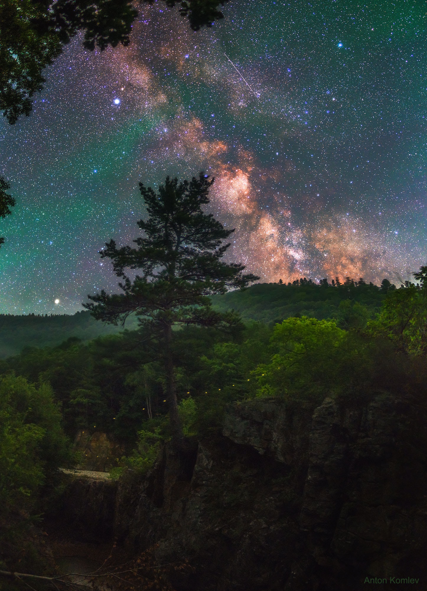 It started with a pine tree. The idea was to photograph a statuesque pine in front of the central band of our Milky Way Galaxy. And the plan, carried out two months ago, was successful -- they both appear prominently. But the resulting 3-frame panorama captured much more. Colorful stars, for example, dot the distant background, with bright Altair visible on the upper left. The planet Saturn, a bit closer, was captured just over the horizon on the far left. Just beyond the Earth's atmosphere, seen in the upper right, an Earth-orbiting satellite was caught leaving a streak during the 25-second exposure. The Earth's atmosphere itself was surprisingly visible -- as green airglow across the image top. Finally, just by chance, there was a firefly. Do you see it? Near the image bottom, the firefly blinked in yellow several times as it fluttered before the rolling hills above Milogradovka River in Primorsky Krai, Russia. Explore Your Universe: Random APOD Generator