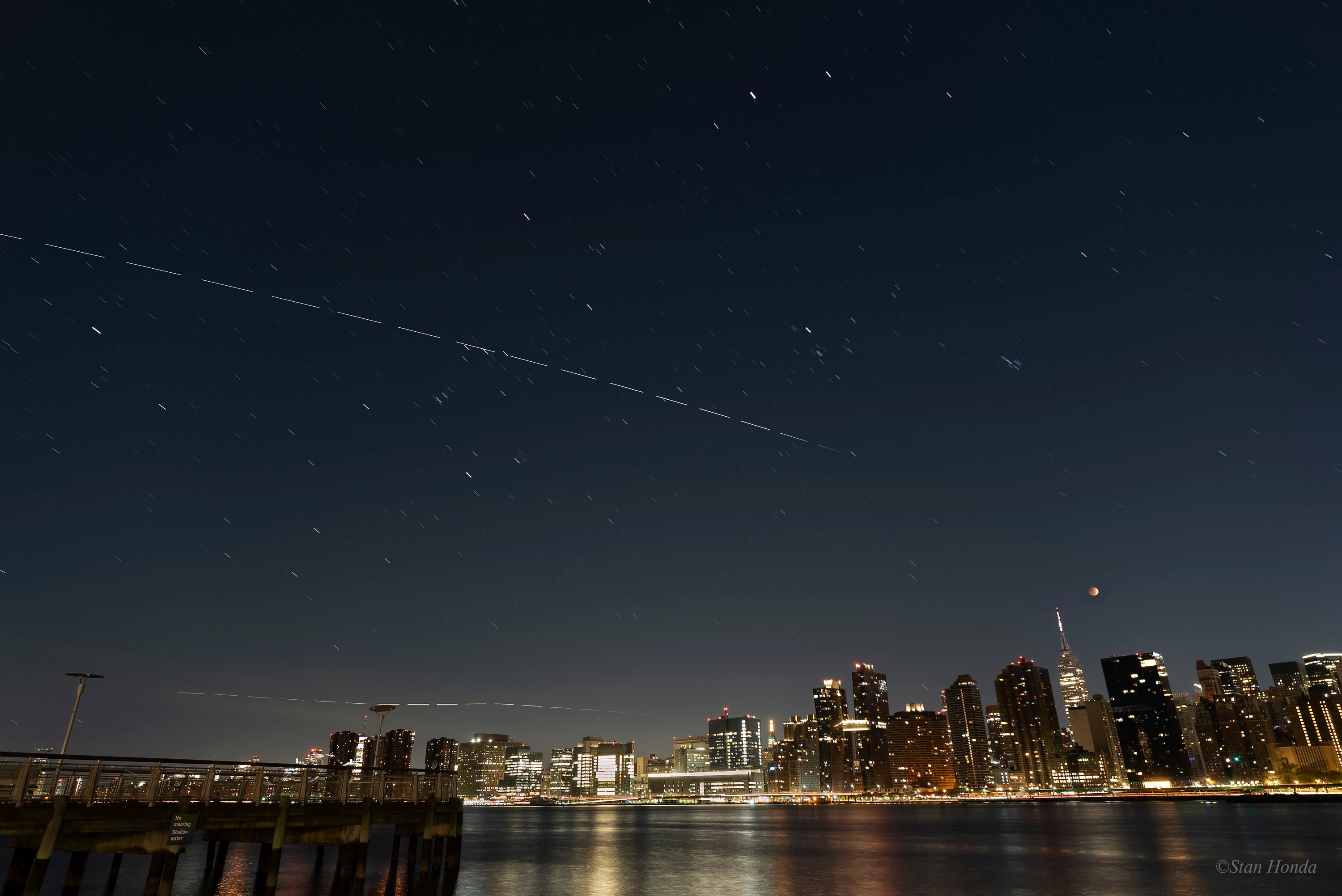 A darker Moon sets over Manhattan in this night skyscape. The 16 frame composite was assembled from consecutive exposures recorded during the November 8 total lunar eclipse. In the timelapse sequence stars leave short trails above the urban skyline, while the Moon remains immersed in Earth's shadow. But the International Space Station was just emerging from the shadow into the sunlit portion of its low Earth orbit. As seen from New York City, the visible streak of this ISS flyover starts near a star in Taurus and tracks right to left, through the belt of Orion and over Sirius, alpha star of Canis Major. Gaps along the bright trail of the fast moving orbital outpost (and an aircraft flying closer to the horizon) mark the time between individual exposures in the sequence. The trail of bright planet Mars is at the top of the frame. Pleiades star cluster trails are high over the eclipsed Moon and Empire State Building. Lunar Eclipse of November 2022: Notable Submissions to APOD Love Eclipses? (US): Apply to become a NASA Partner Eclipse Ambassador