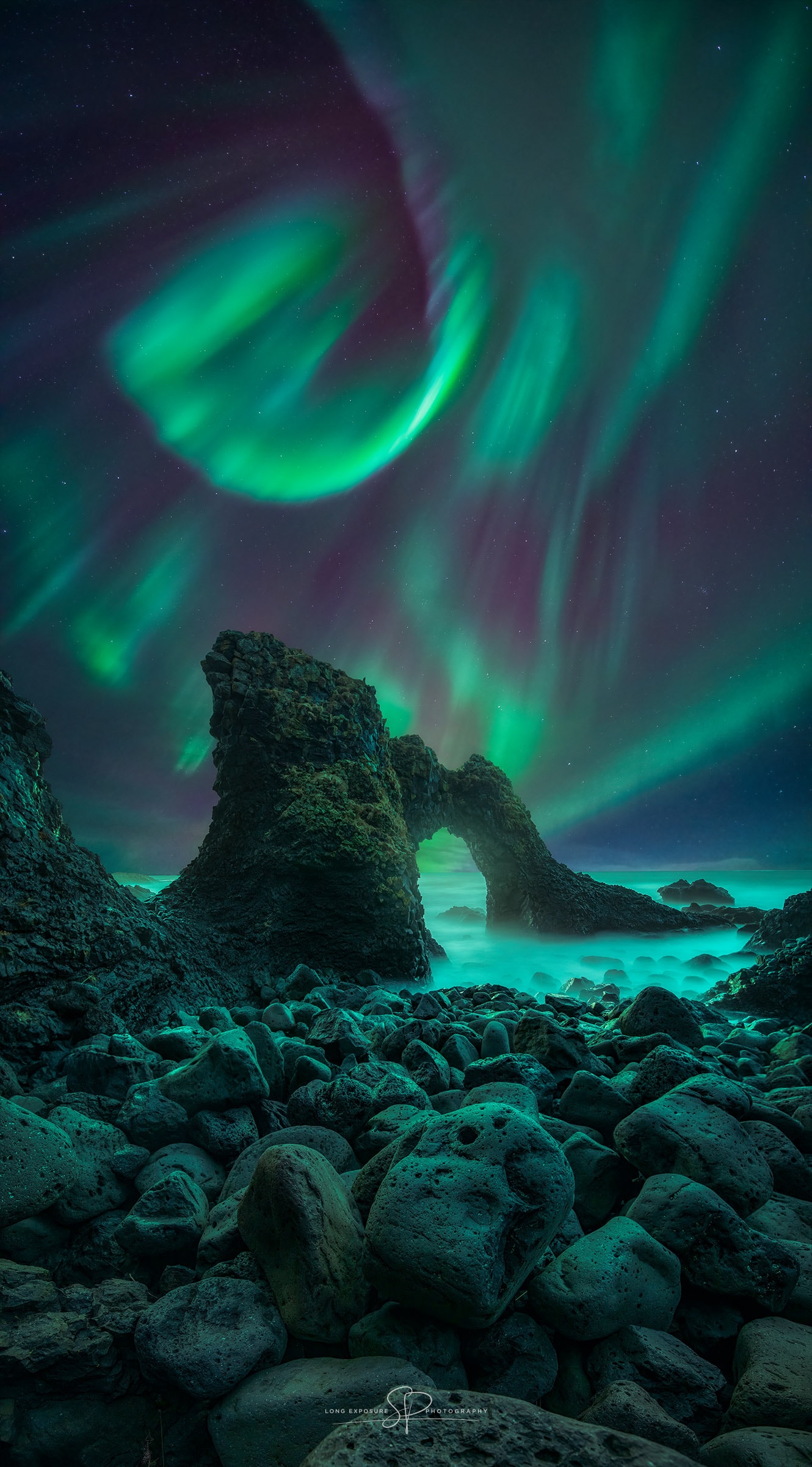 The scene may look like a fantasy, but it's really Iceland. The rock arch is named Gatklettur and located on the island's northwest coast. Some of the larger rocks in the foreground span a meter across. The fog over the rocks is really moving waves averaged over long exposures. The featured image is a composite of several foreground and background shots taken with the same camera and from the same location on the same night last November. The location was picked for its picturesque foreground, but the timing was planned for its colorful background: aurora. The spiral aurora, far behind the arch, was one of the brightest seen in the astrophotographer's life. The coiled pattern was fleeting, though, as auroral patterns waved and danced for hours during the cold night. Far in the background were the unchanging stars, with Earth's rotation causing them to appear to slowly circle the sky's northernmost point near Polaris. Your Sky Surprise: What picture did APOD feature on your birthday? (post 1995)