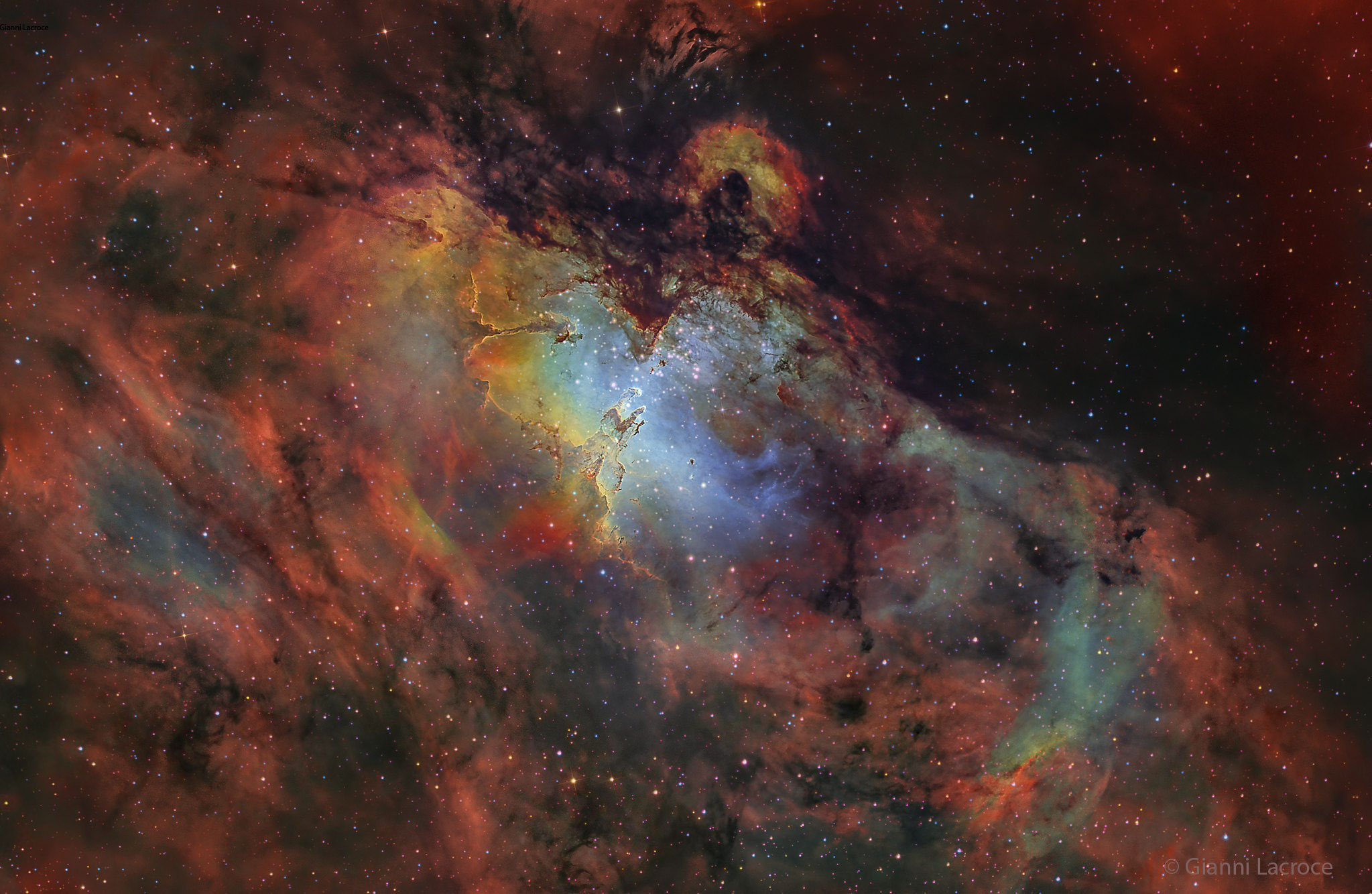 From afar, the whole thing looks like an eagle. A closer look at the Eagle Nebula, however, shows the bright region is actually a window into the center of a larger dark shell of dust. Through this window, a brightly-lit workshop appears where a whole open cluster of stars is being formed. In this cavity, tall pillars and round globules of dark dust and cold molecular gas remain where stars are still forming. Already visible are several young bright blue stars whose light and winds are burning away and pushing back the remaining filaments and walls of gas and dust. The Eagle emission nebula, tagged M16, lies about 6500 light years away, spans about 20 light-years, and is visible with binoculars toward the constellation of the Serpent (Serpens). This picture involved long and deep exposures and combined three specific emitted colors emitted by sulfur (colored as yellow), hydrogen (red), and oxygen (blue).