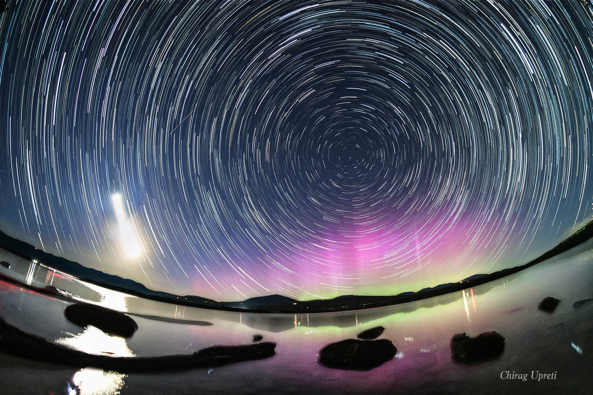 Graceful star trail arcs reflect planet Earth's daily rotation in this colorful night skyscape. To create the timelapse composite, on May 12 consecutive exposures were recorded with a camera fixed to a tripod on the shores of the Ashokan Reservoir, in the Catskills region of New York, USA. North star Polaris is near the center of the star trail arcs. The broad trail of a waxing crescent Moon is on the left, casting a strong reflection across the reservoir waters. With intense solar activity driving recent geomagnetic storms, the colorful aurora borealis or northern lights, rare to the region, shine under Polaris and the north celestial pole. AuroraSaurus: Report your aurora observations