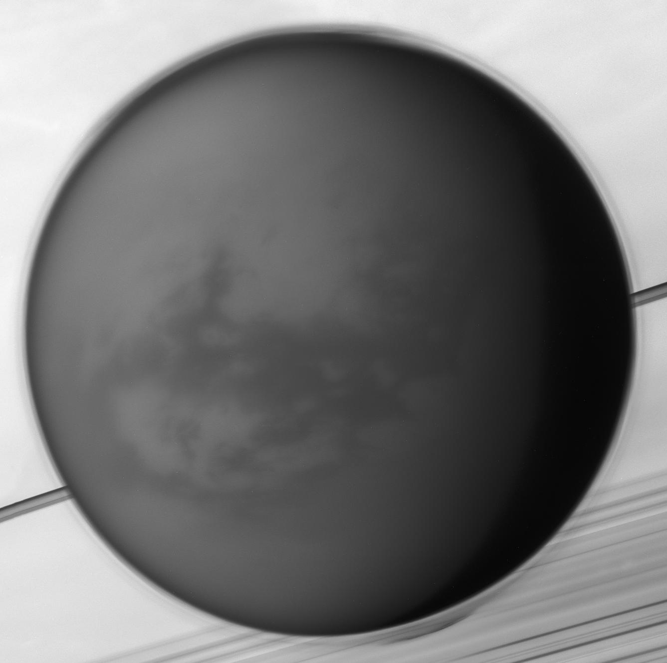 Like Earth's moon, Saturn's largest moon Titan is locked in synchronous rotation with its planet. This mosaic of images recorded by the Cassini spacecraft in May of 2012 shows its anti-Saturn side, the side always facing away from the ringed gas giant. The only moon in the solar system with a dense atmosphere, Titan is the only solar system world besides Earth known to have standing bodies of liquid on its surface and an earthlike cycle of liquid rain and evaporation. Its high altitude layer of atmospheric haze is evident in the Cassini view of the 5,000 kilometer diameter moon over Saturn's rings and cloud tops. Near center is the dark dune-filled region known as Shangri-La. The Cassini-delivered Huygens probe rests below and left of center, after the most distant landing for a spacecraft from Earth.