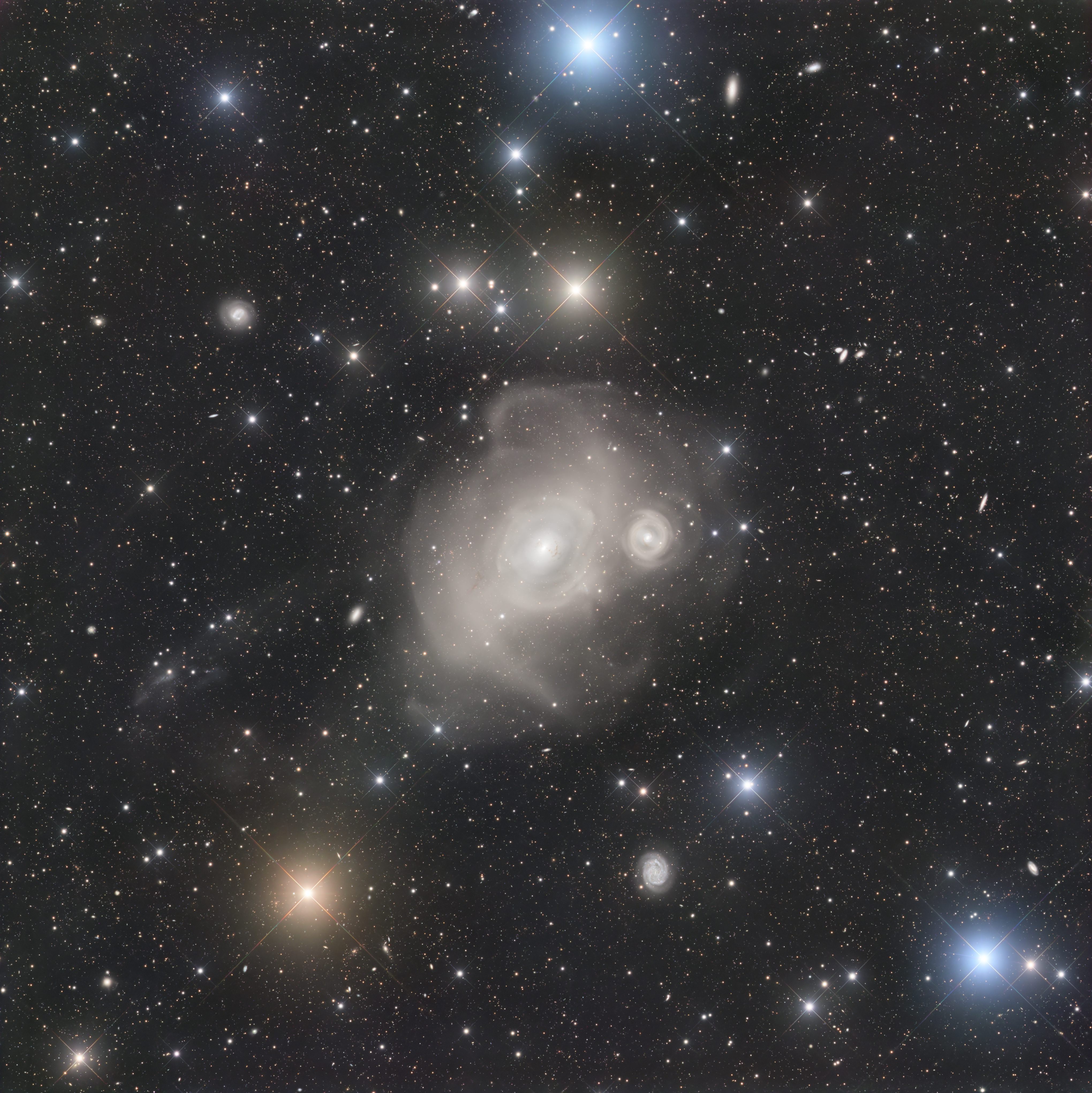 An example of violence on a cosmic scale, enormous elliptical galaxy NGC 1316 lies about 75 million light-years away toward Fornax, the southern constellation of the Furnace. Investigating the startling sight, astronomers suspect the giant galaxy of colliding with smaller neighbor NGC 1317 seen just right of the large galaxy's center, producing far flung star streams in loops and shells. Light from their close encounter would have reached Earth some 100 million years ago. In the sharp telescopic image, the central regions of NGC 1316 and NGC 1317 appear separated by over 100,000 light-years. Complex dust lanes visible within also indicate that NGC 1316 is itself the result of a merger of galaxies in the distant past. Found on the outskirts of the Fornax galaxy cluster, NGC 1316 is known as Fornax A. One of the visually brightest of the Fornax cluster galaxies it is one of the strongest and largest celestial radio sources with radio emission extending well beyond this one degree wide field-of-view.
