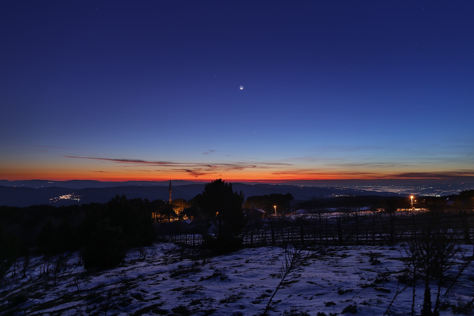 Only two days after the February New Moon's annular eclipse of the Sun, a slender lunar crescent poses above the western horizon after sunset in this wintry twilight skyscape. Its nightside faintly illuminated by earthshine, the young Moon is joined by three bright planets in the mostly clear, early evening skies above the village of Kirazli, Turkiye. Inner planet Venus appears closest to the horizon. Near the beginning of its 2026 performance as planet Earth's evening star, brilliant Venus is seen through the warm sunset glare near picture center. Straight above Venus, innermost planet Mercury is easy to spot as it stands remarkably high above the horizon even as the twilight sky is growing dark. Outer planet Saturn, most distant of the naked-eye planets, is found just left of the Moon's sunlit crescent.