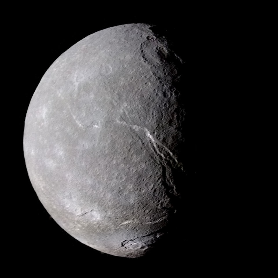 Titania's tortured terrain is a mix of canyons, cliffs, and craters. NASA's interplanetary robot spacecraft Voyager 2 passed the largest moon of Uranus in 1986 and took the feature picture. That the trenches of Titania resemble those on another moon of Uranus, Ariel, indicate that Titania underwent some violent surface event possibly related to water freezing and expanding in its distant past. Although Titania is Uranus's largest moon, it is only about half the radius of Triton - the largest moon of Uranus's sister planet Neptune, which itself is slightly smaller than Earth's Moon. Titania, discovered by William Herschel in 1787, is essentially a large dirty iceball that is composed of about half water-ice and half rock. There is recent speculation that radioactive heating melts some underground ice into oceans.