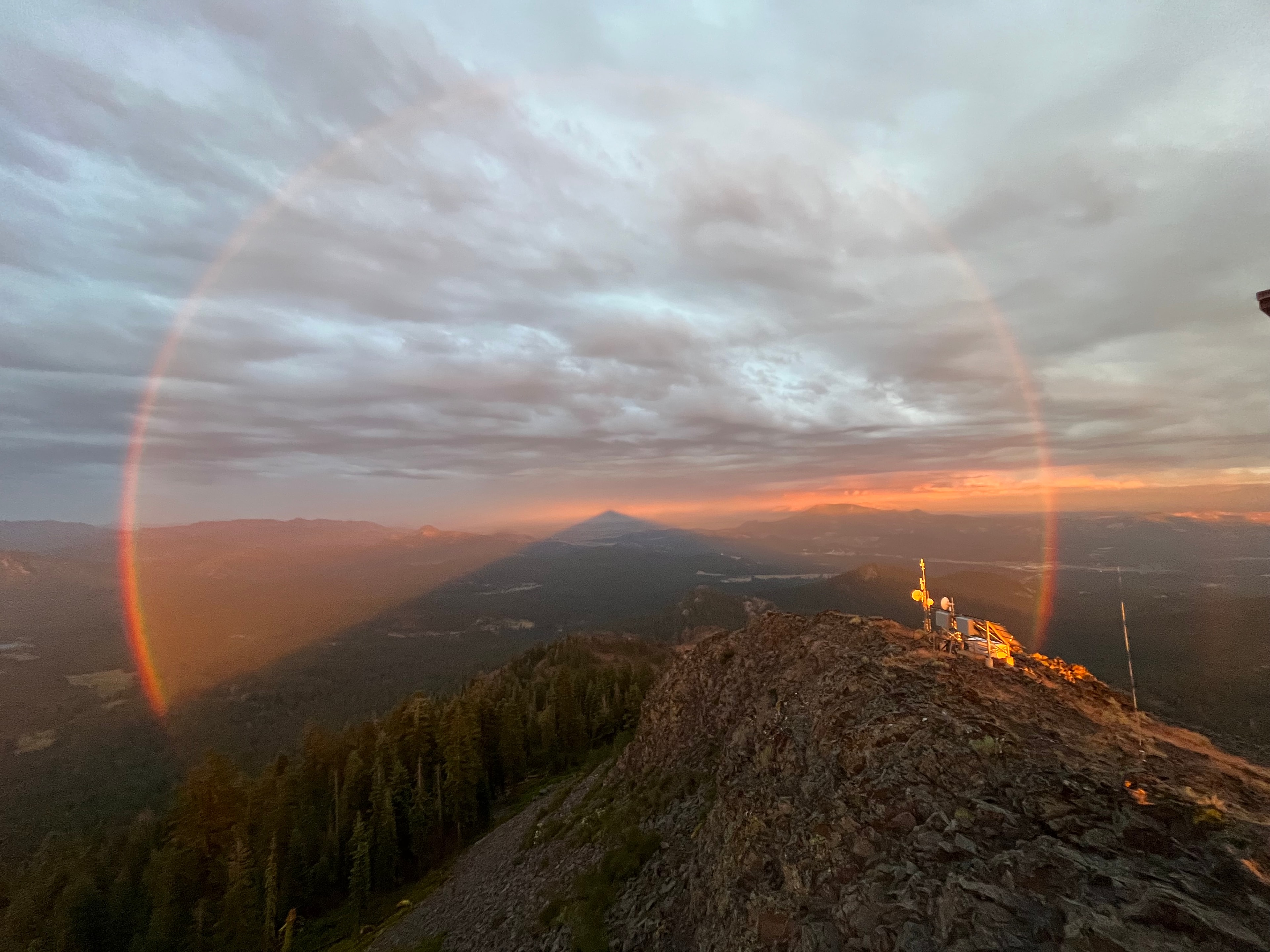 At sunset, an alignment of rainbow and mountain shadow was captured in this remarkable snapshot. The stunning view was recorded from a fire lookout on Smith Peak in the Plumas National Forest near Portola, California on July 13. Still, near sunset it's no accident that the majestic mountain shadow seems to point to the center of the graceful rainbow arc. Due to perspective and the long line of sight the mountain shadow naturally forms a tapering triangular shape, its apex positioned at the point opposite the Sun on the horizon. Following thunderstorms across the region, the rainbow arcs across the early evening sky, with its colorful and characteristic 42 degree arc formed as sunlight is refracted and reflected by the atmospheric water droplets. The geometric center of a rainbow arc lies at the antisolar point. And in this scene from the golden hour on planet Earth, that's also oposite the setting Sun along the distant horizon.